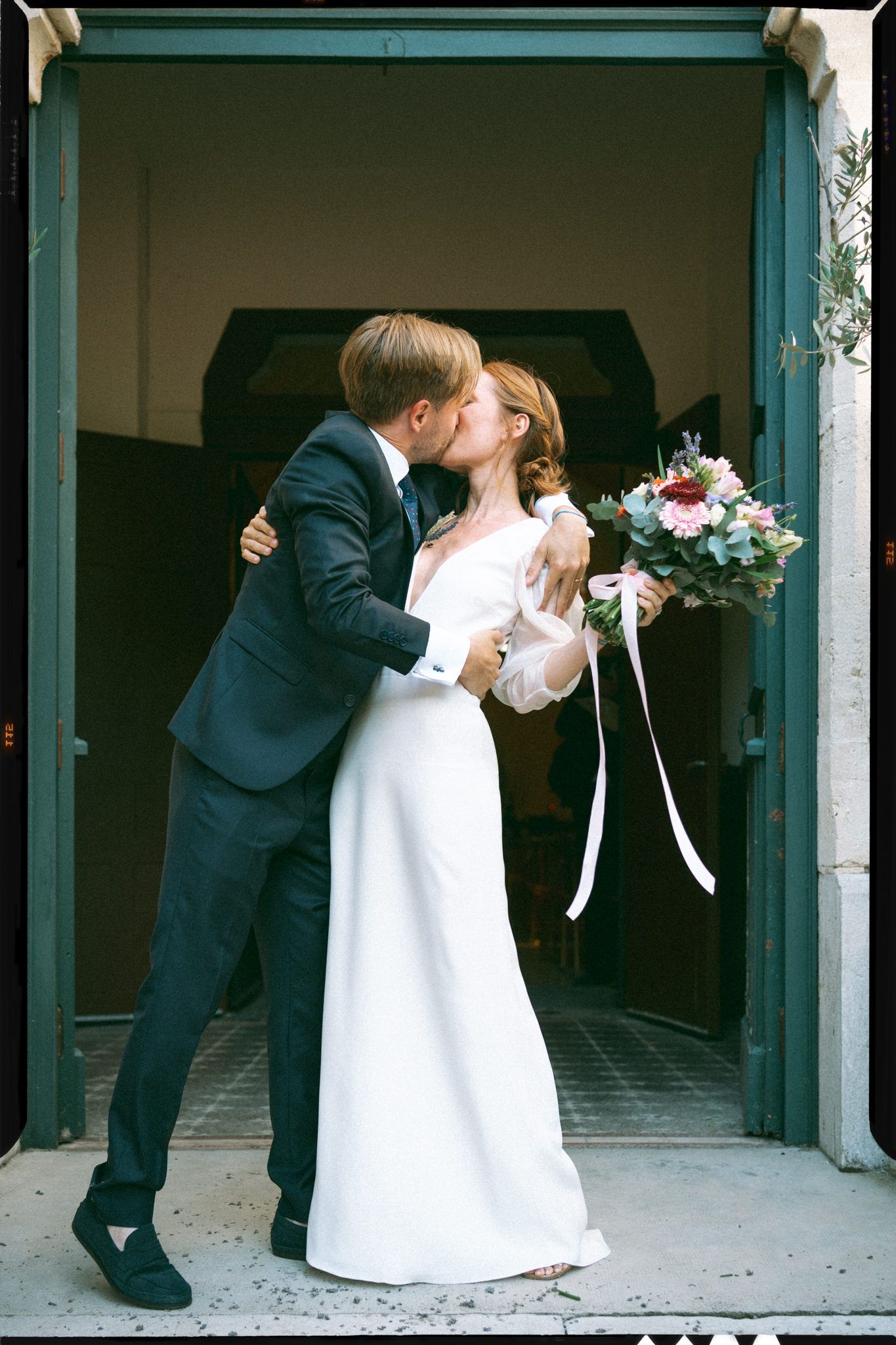 Romantic wedding couple sharing intimate moments at a church entrance.