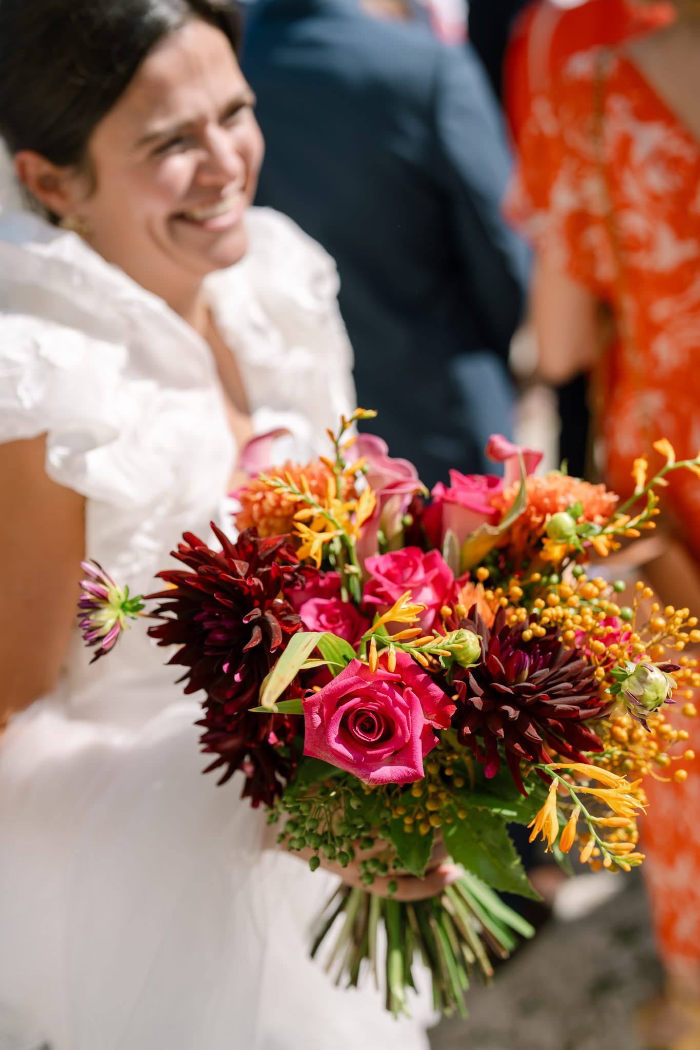 Vibrant fall wedding bouquet with deep burgundy dahlias, pink roses and orange accents.