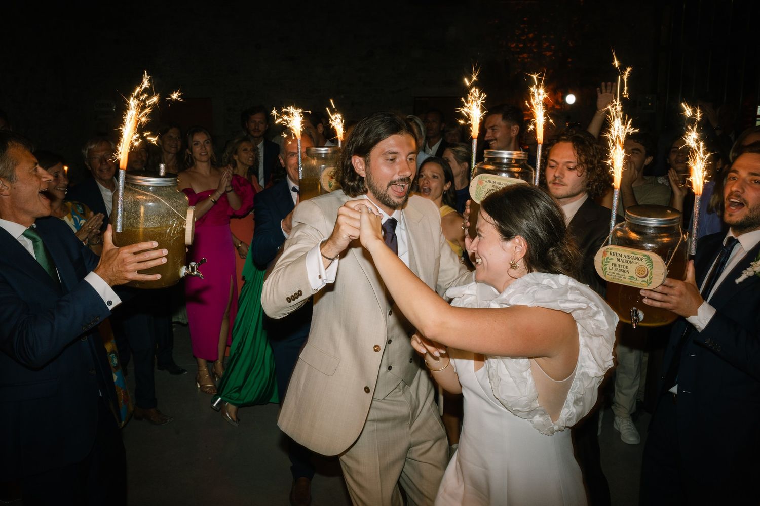 Party guests celebrate on a dimly lit dance floor with sparklers creating a festive atmosphere.