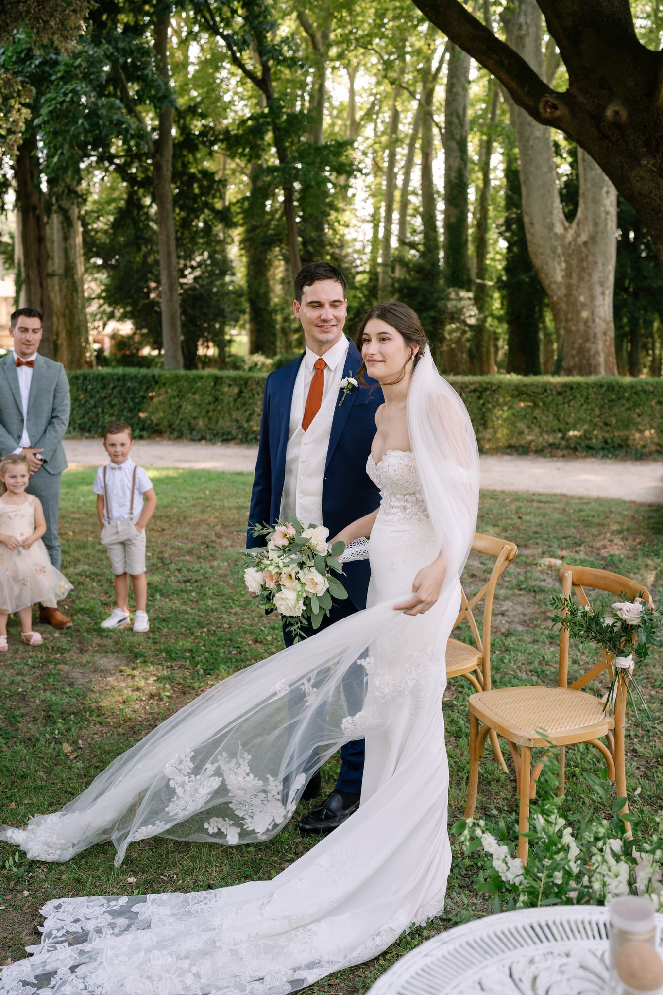 Wedding portraits in a garden setting with flowing veil and natural sunlight.