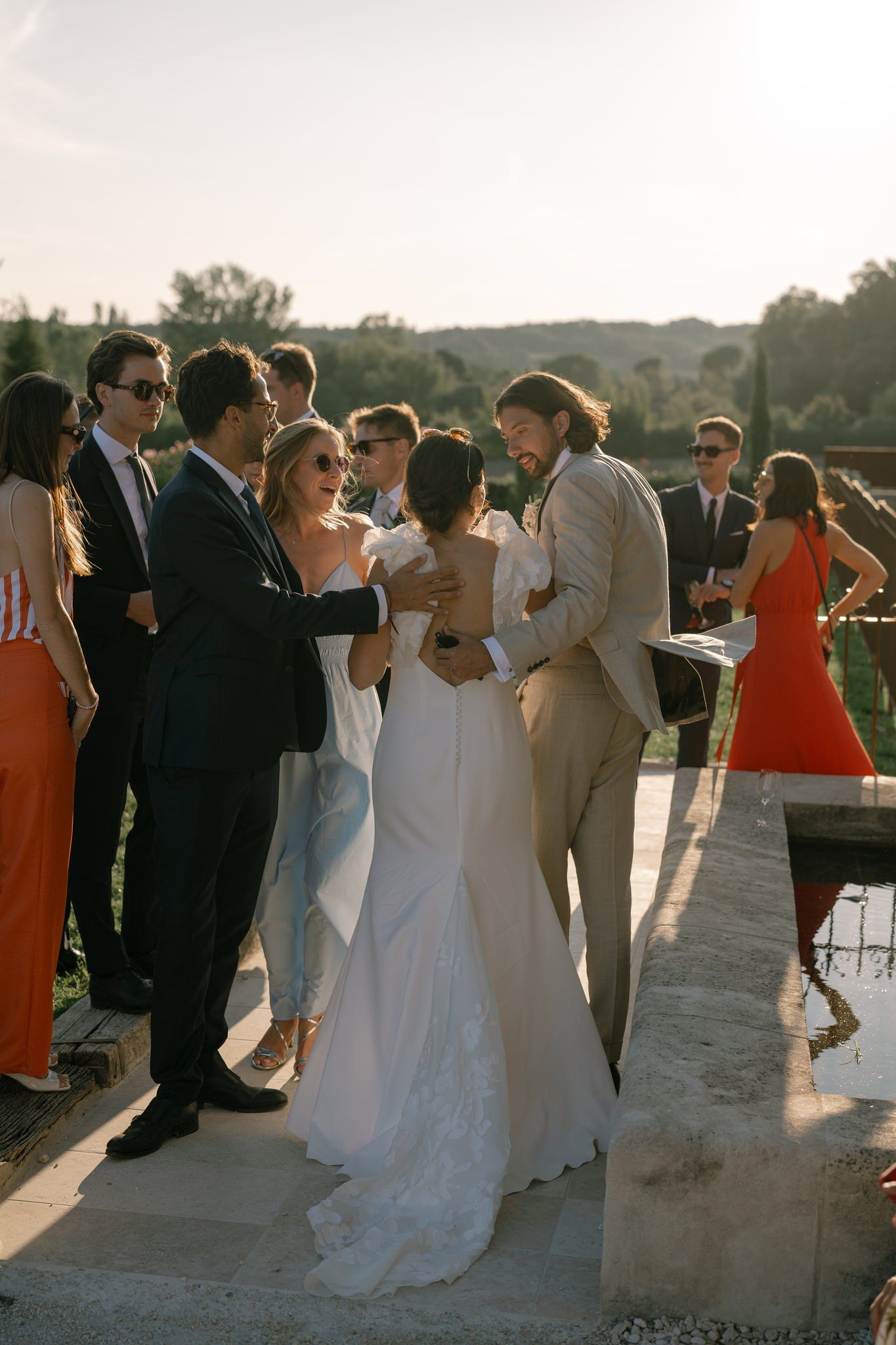 Wedding party and guests dancing at sunset on an outdoor terrace.