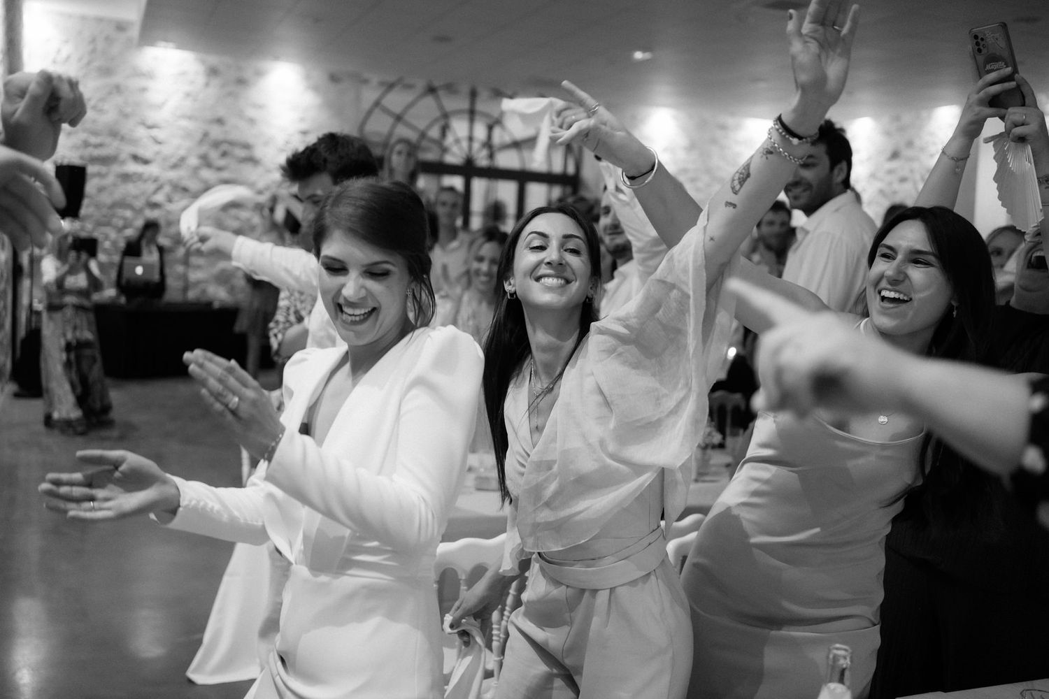 Wedding guests dancing and celebrating with enthusiasm on the dance floor.