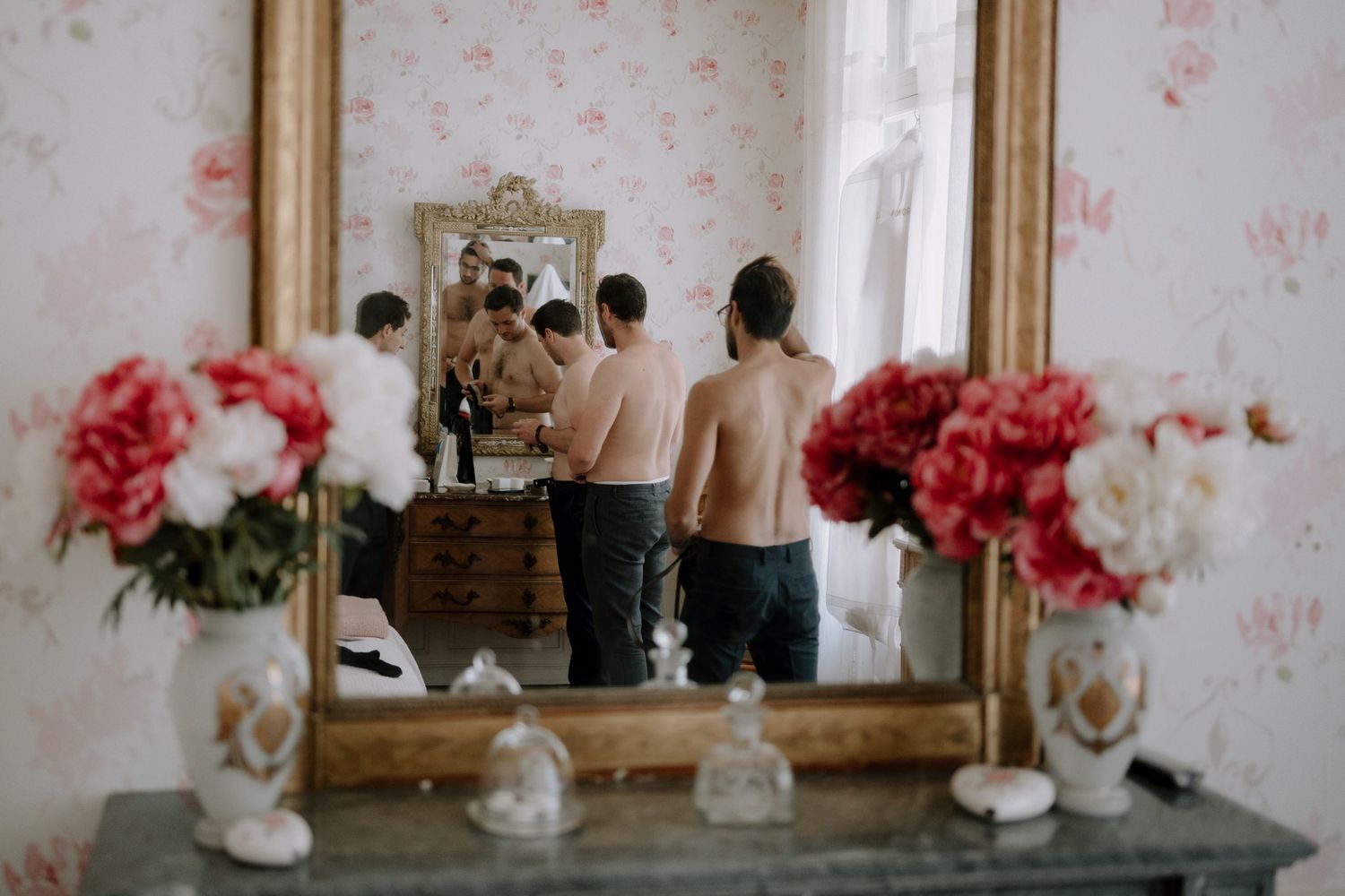 Vintage mirror reflection with pink floral decorations on vanity table.
