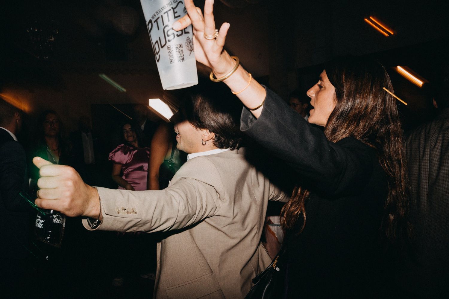 Wedding guests dancing and celebrating at a lively nighttime reception party.