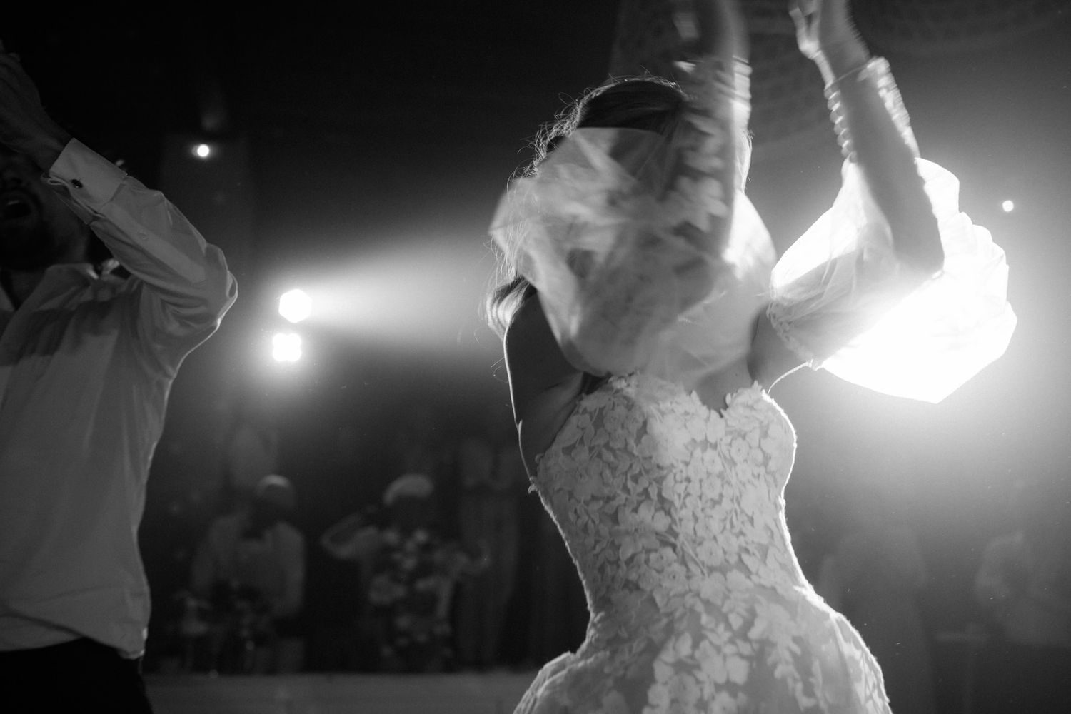 Artistic black and white silhouettes of wedding dancers in motion with dramatic lighting.