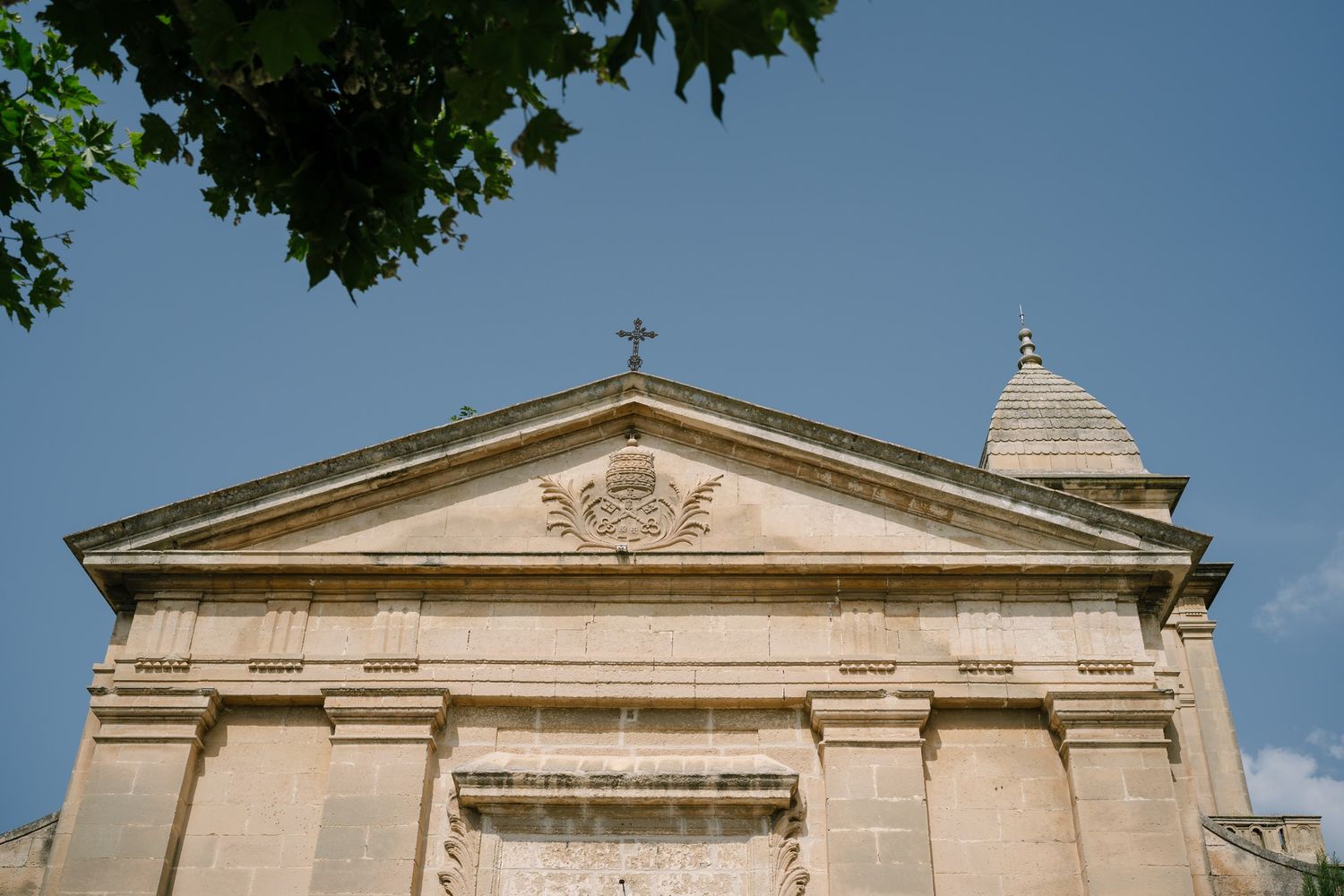 Exterior view of a classical stone church building with ornate architectural details and a cross on top.