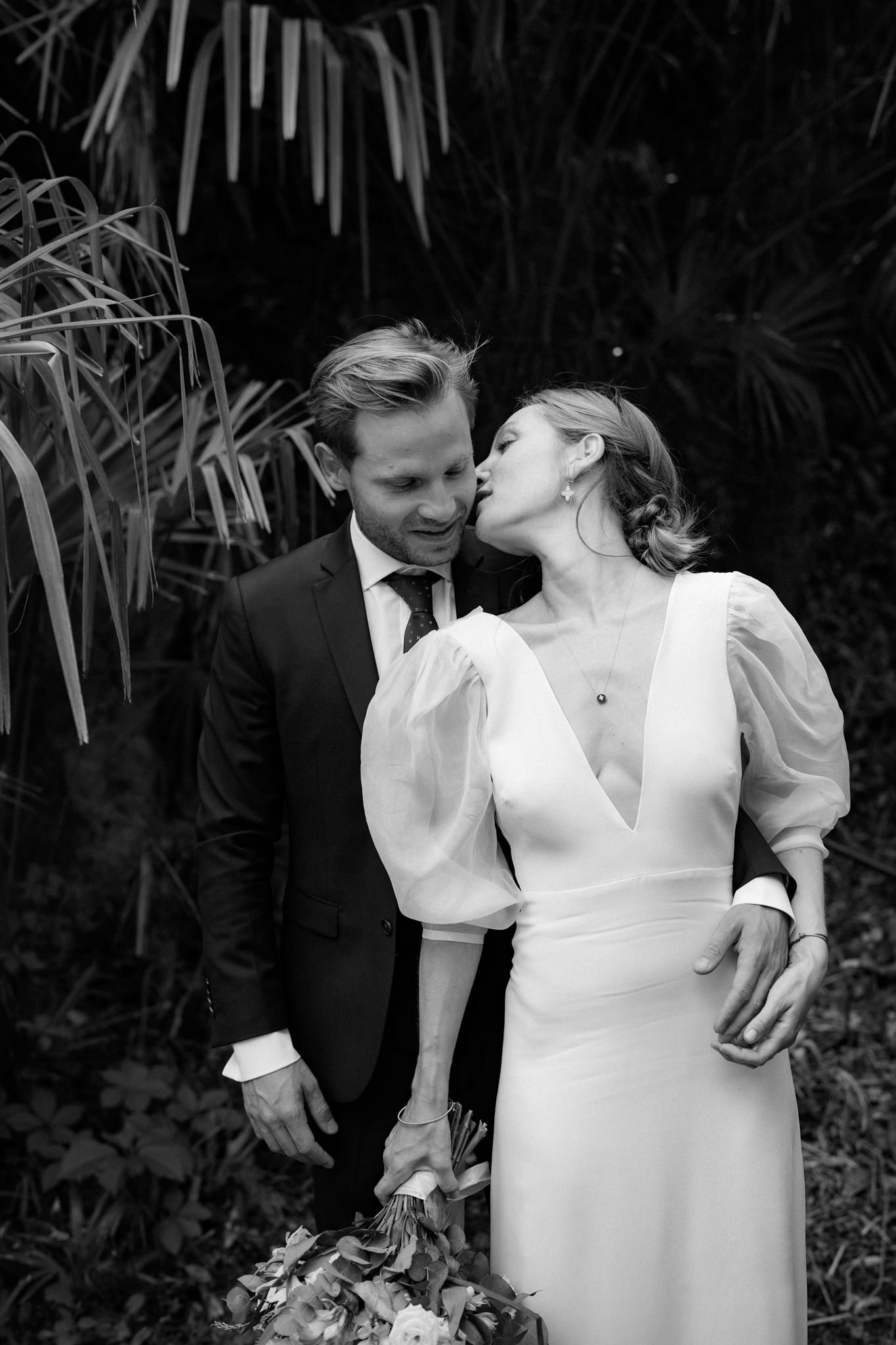 Romantic black and white wedding portrait in a natural garden setting.