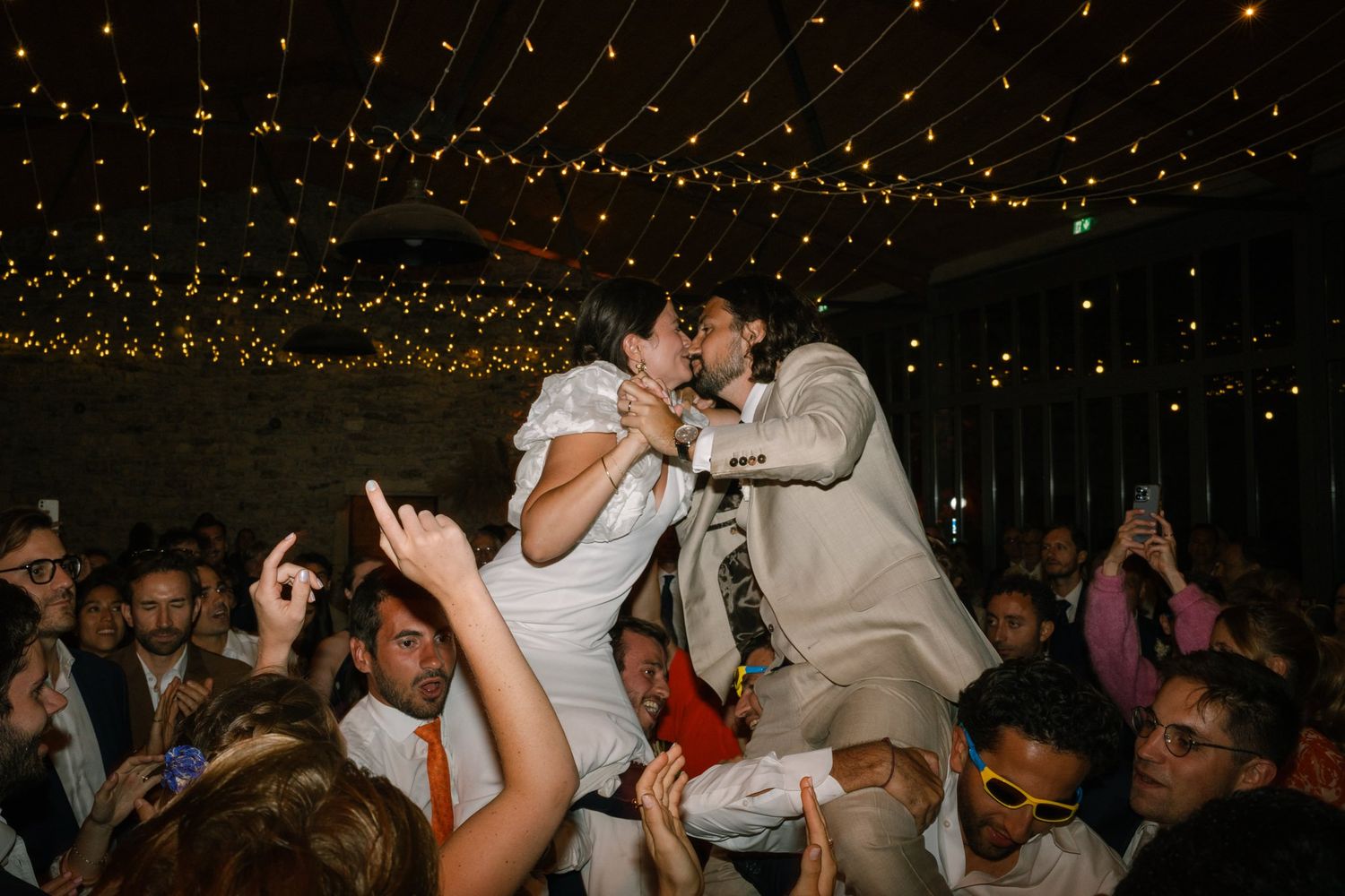 Guests dancing under warm string lights at an evening celebration.