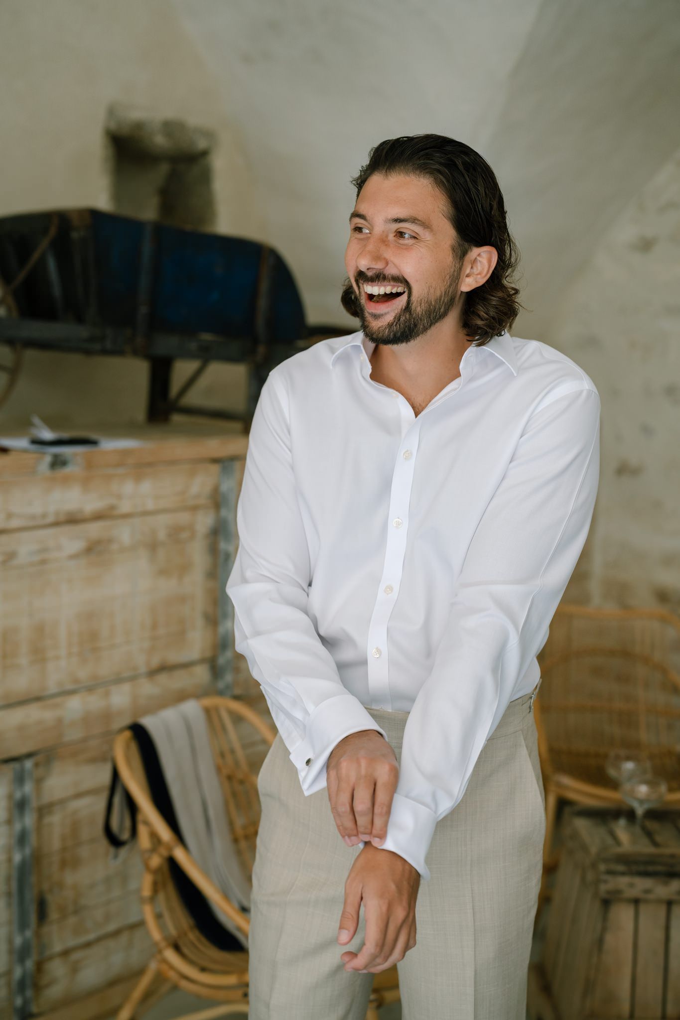 Person in crisp white shirt and khaki pants smiling in casual indoor setting.