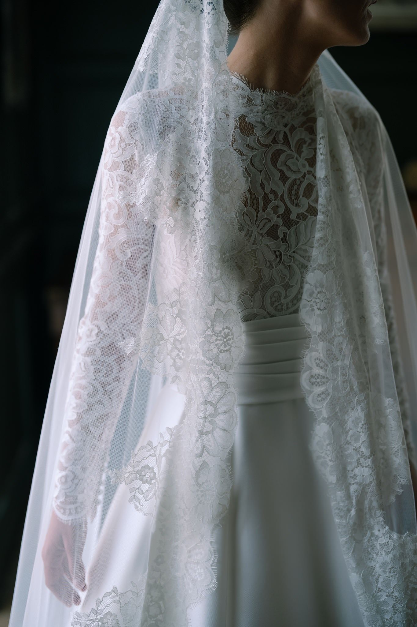 Intricate lace detail on white wedding gown bodice in natural light.