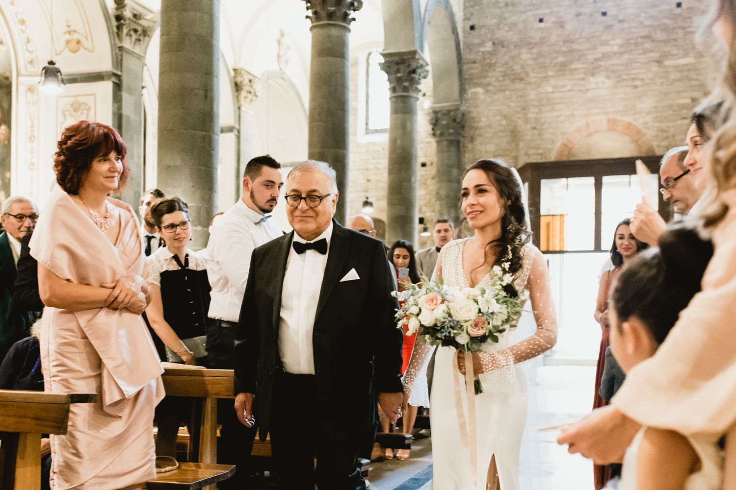 Wedding ceremony in a traditional stone church with guests watching the proceedings.