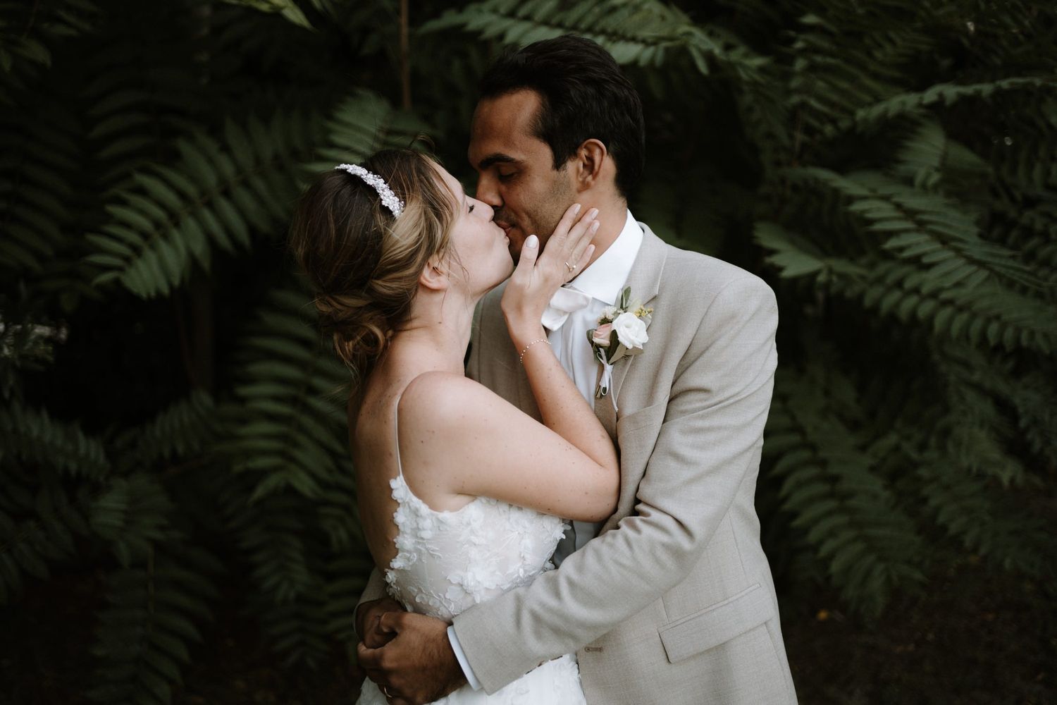 An intimate wedding moment surrounded by lush green ferns and natural foliage.