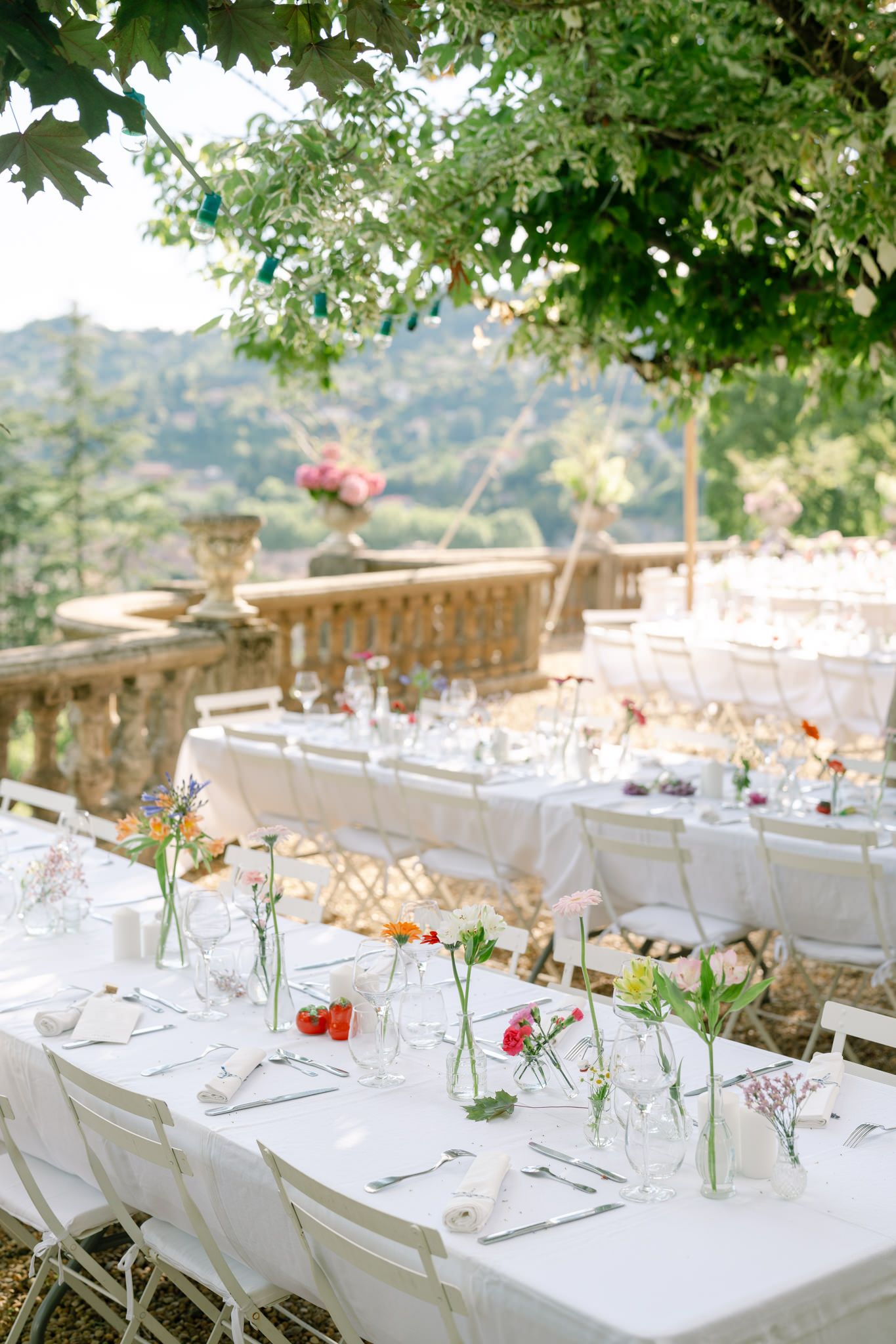 Elegant outdoor wedding table settings with delicate floral centerpieces and mountain views.