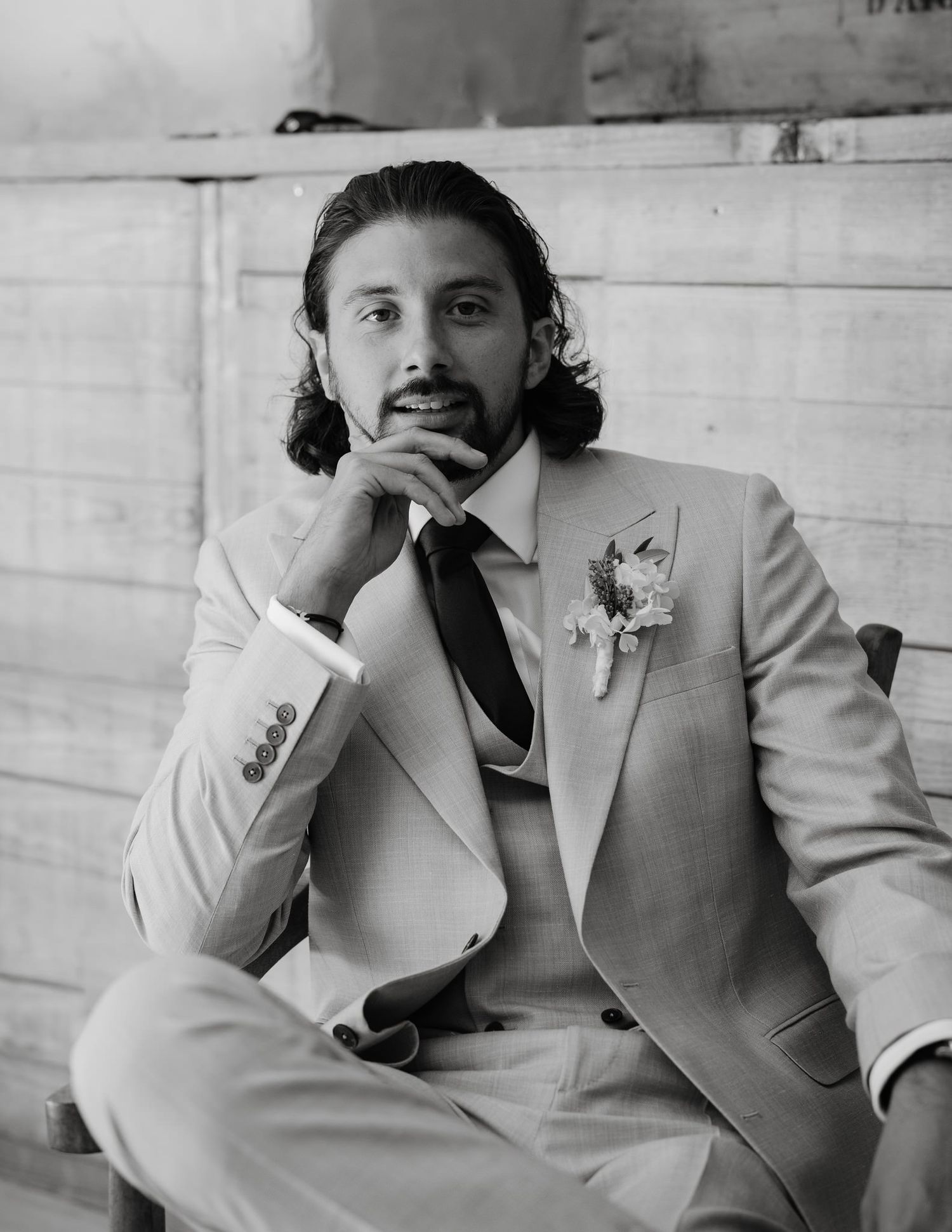 Wedding party members in light gray suits share a candid black and white moment.