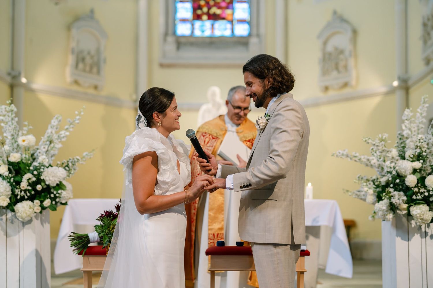 Intimate wedding ceremony taking place in a traditional church with stained glass windows.