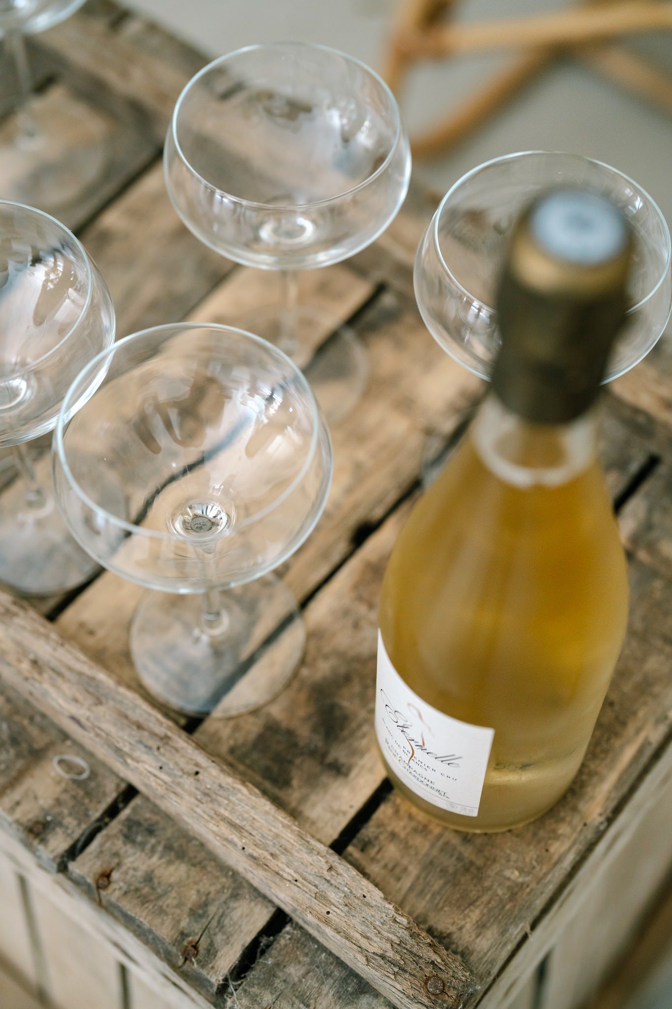 Wine glasses and bottles displayed on weathered wooden crates in rustic setting.