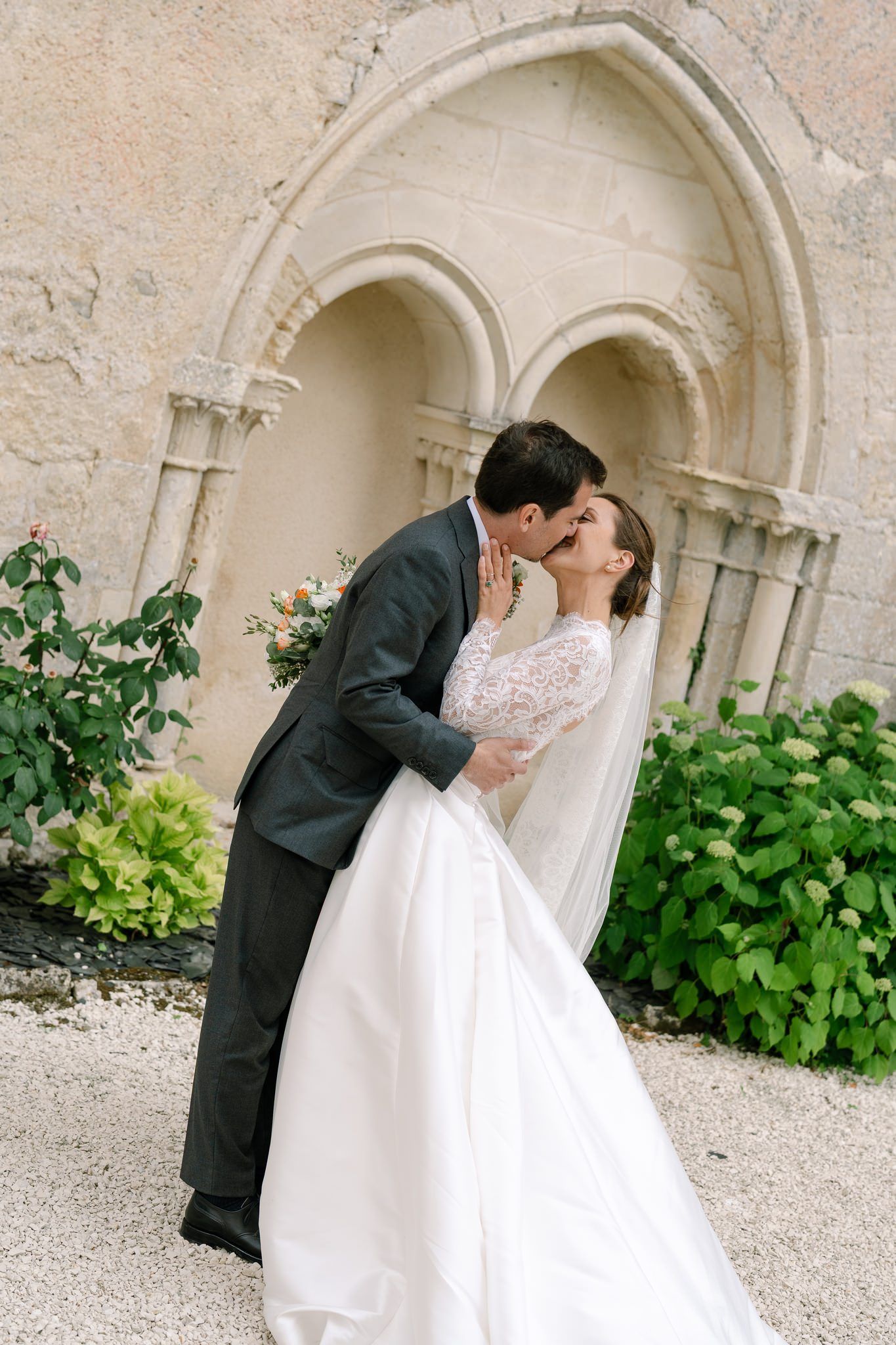 Romantic moment under stone archway at historic wedding venue.