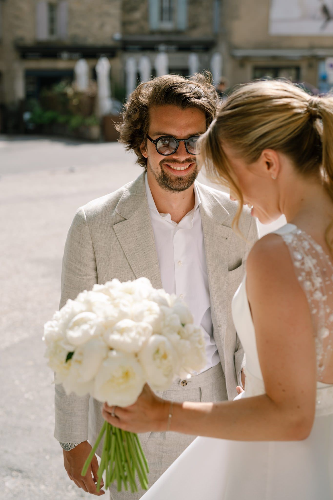 Wedding couple shares intimate moment outdoors with white floral bouquet.