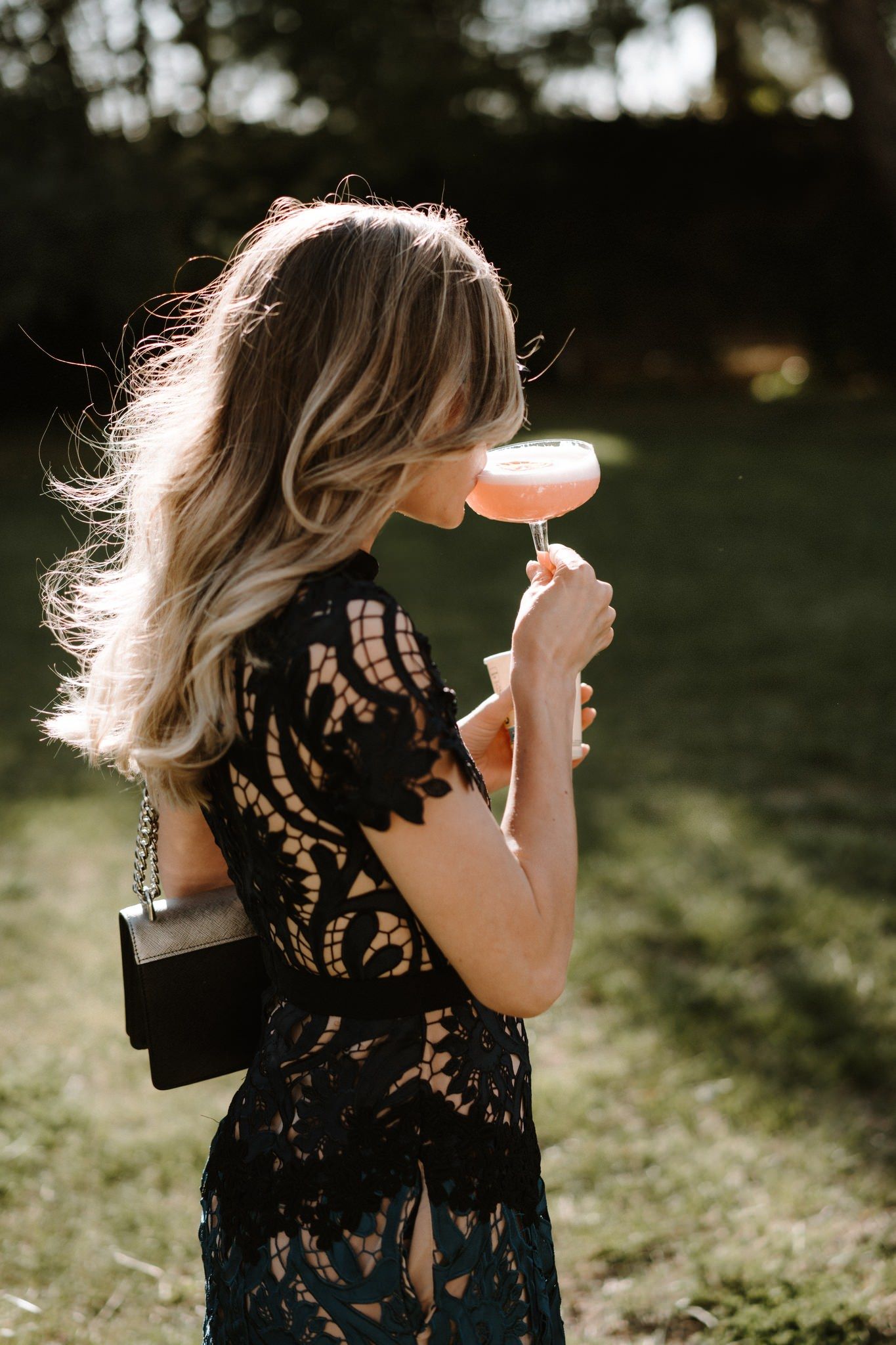 Artistic backlit photos of a woman in a black lace dress outdoors.