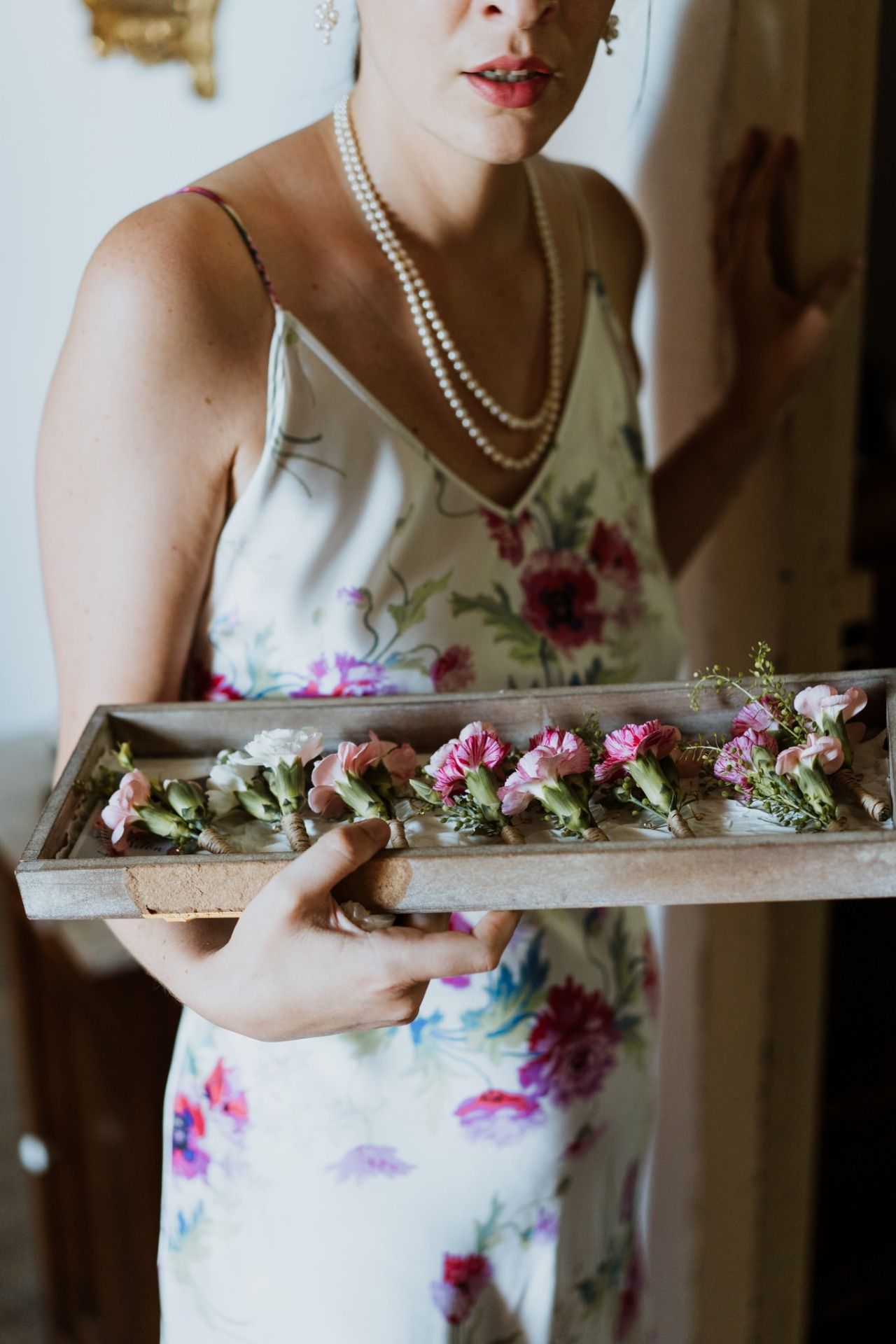 Person holding a wooden plank decorated with small pink and purple flowers.