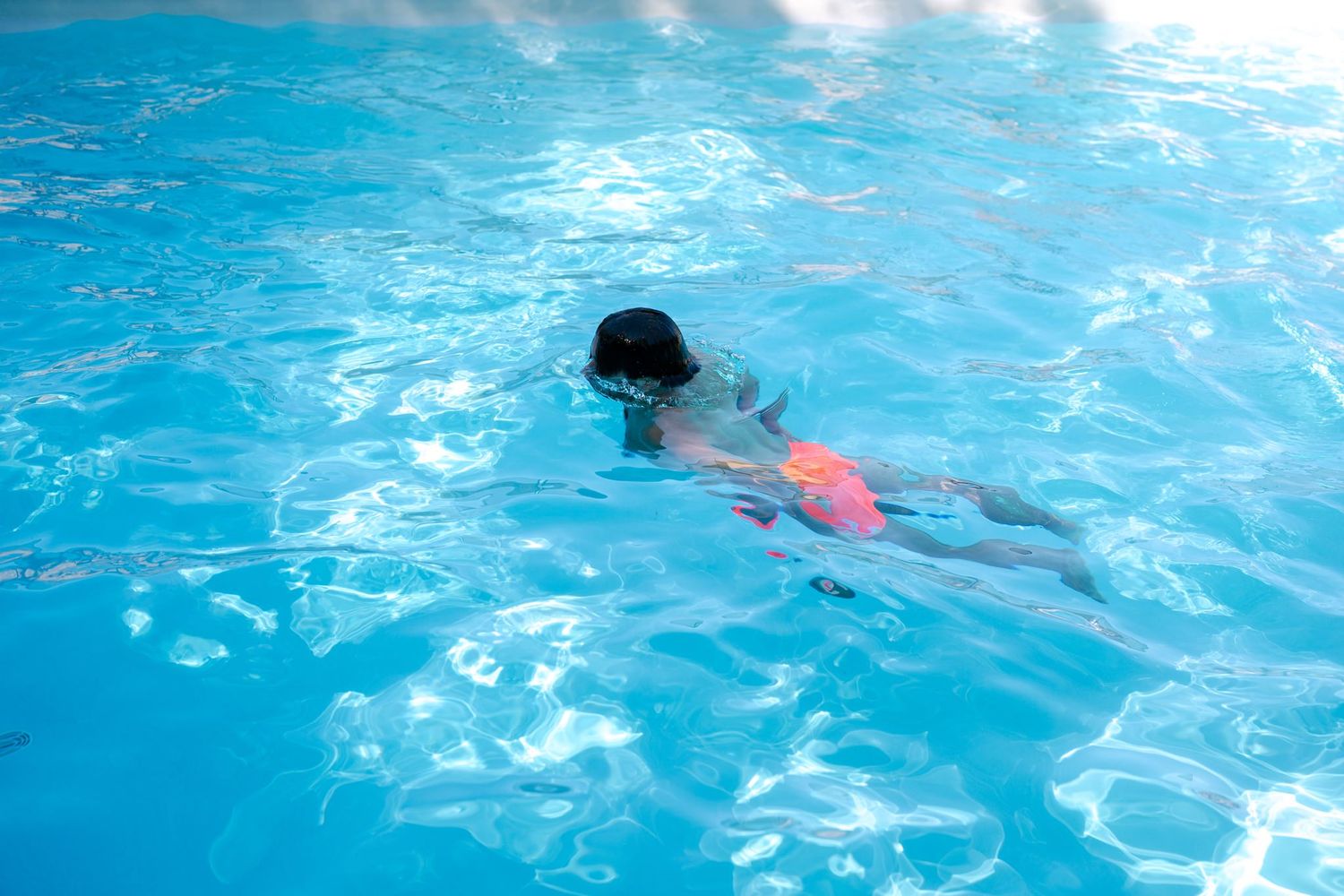 Swimming pool with bright blue water showing swimmers in motion.