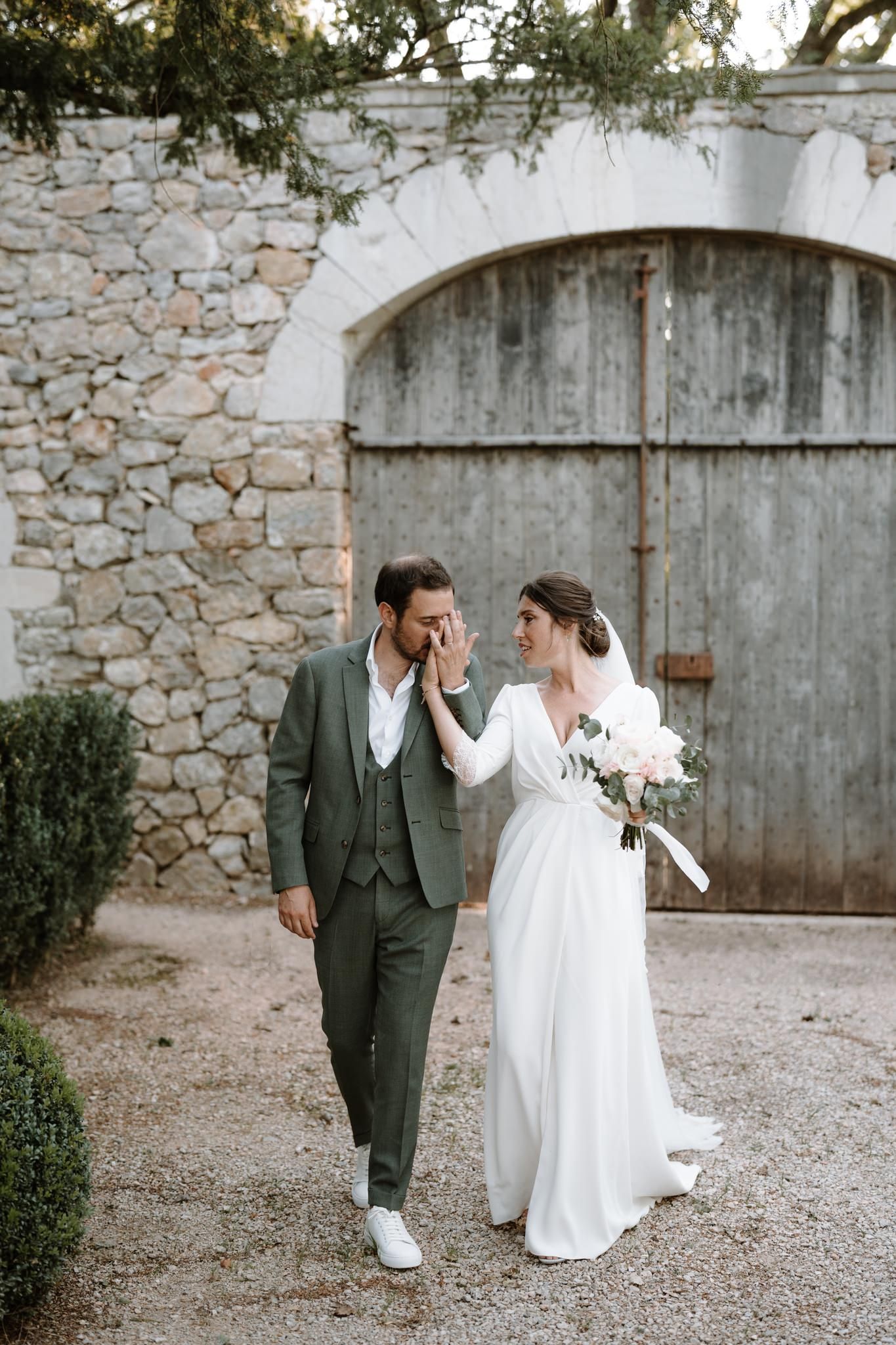 Playful wedding photos against a stone wall showing couple's joyful interactions.