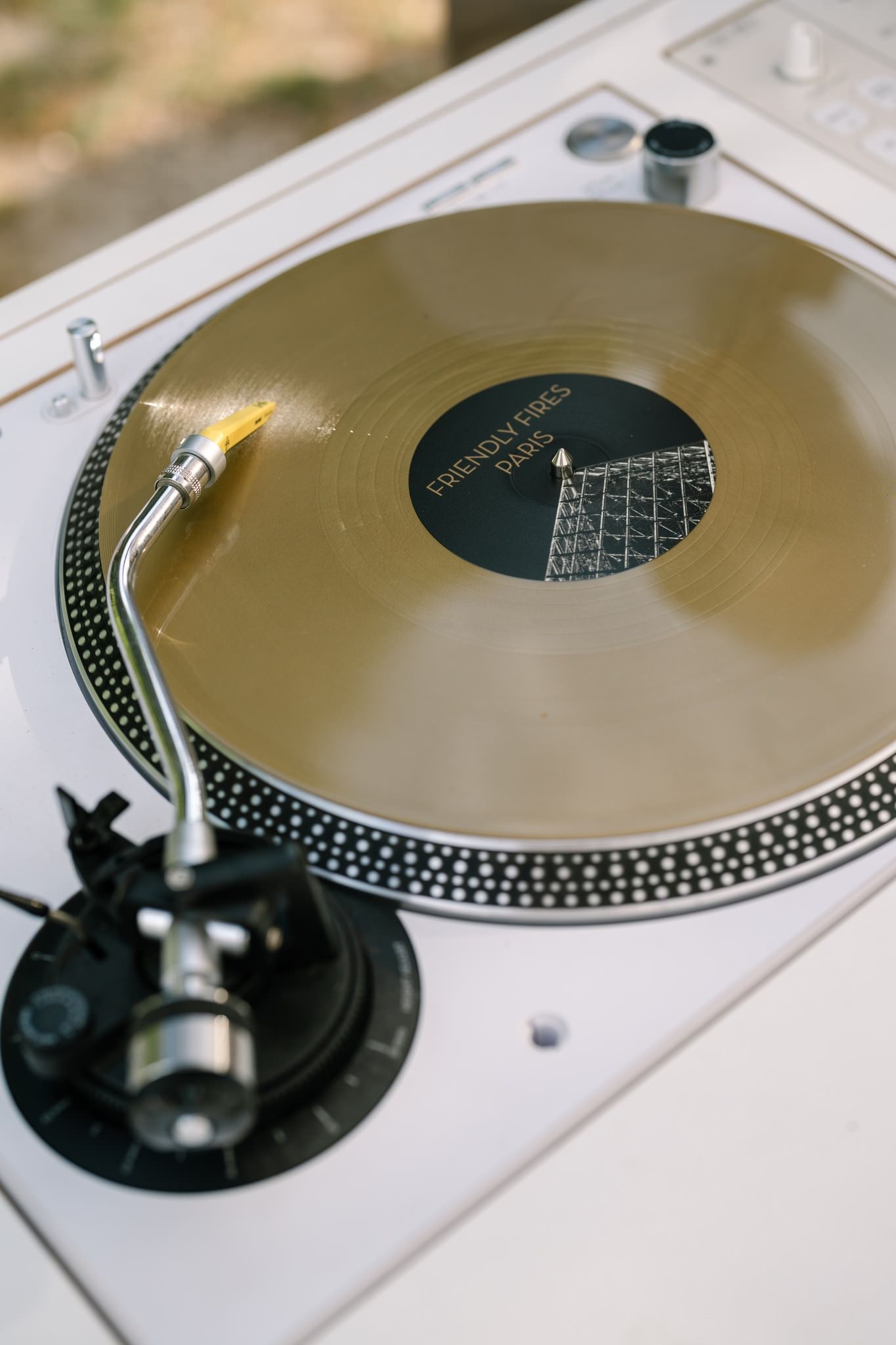 Gold vinyl record spinning on white turntable at wedding reception.