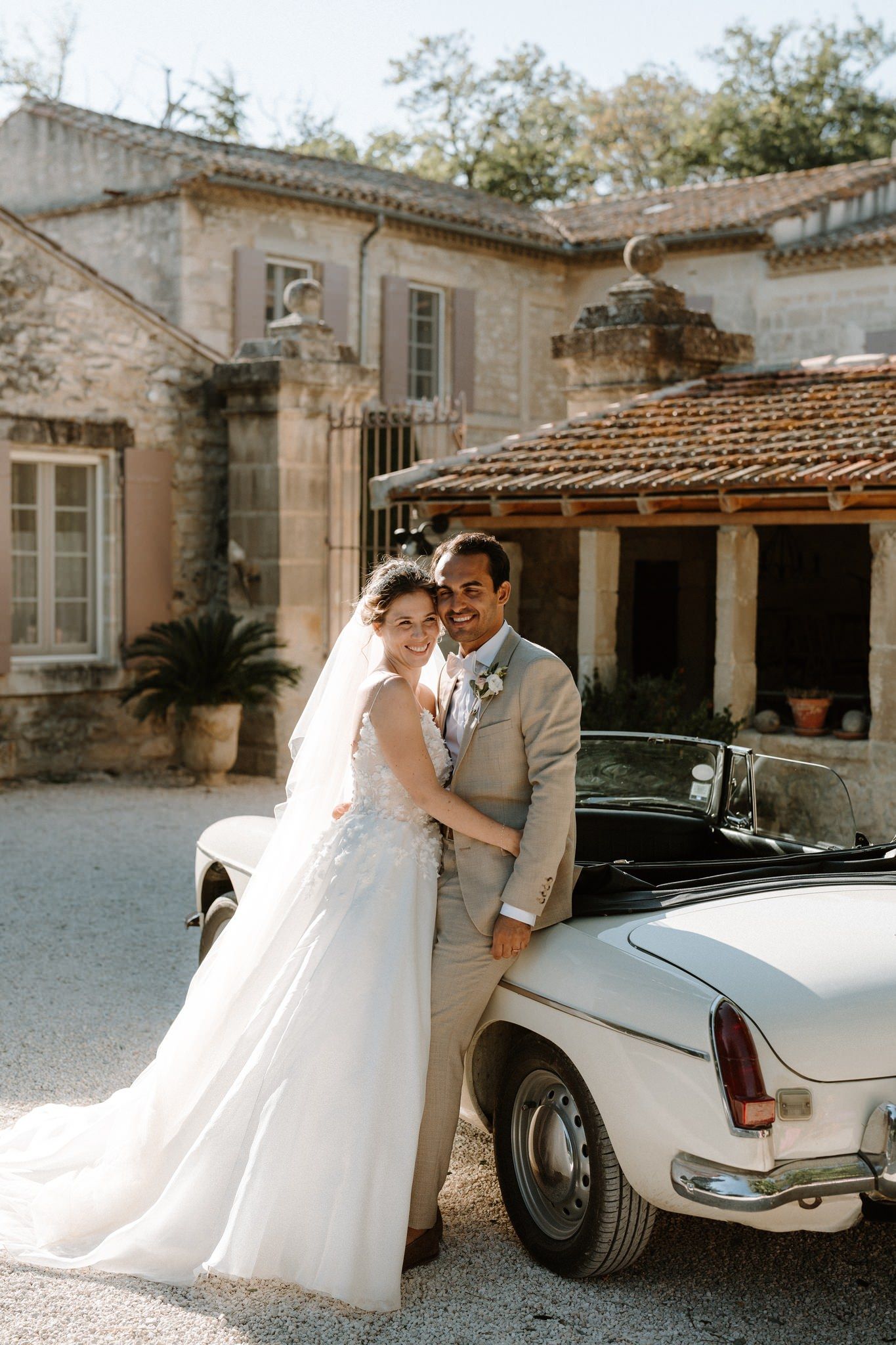 A classic white vintage car parked in front of a Mediterranean-style villa on a sunny day.