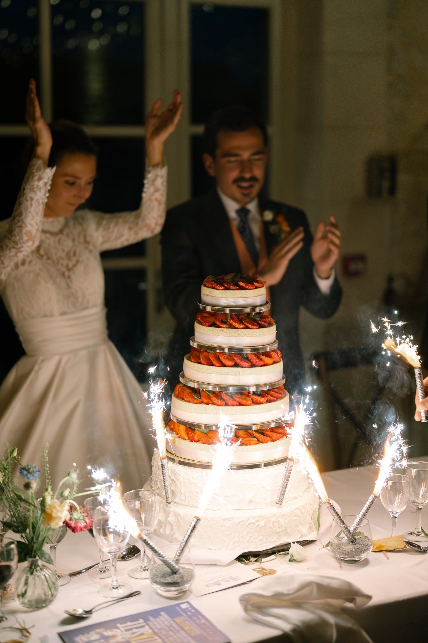 Wedding cake with sparklers on display at an elegant reception table.