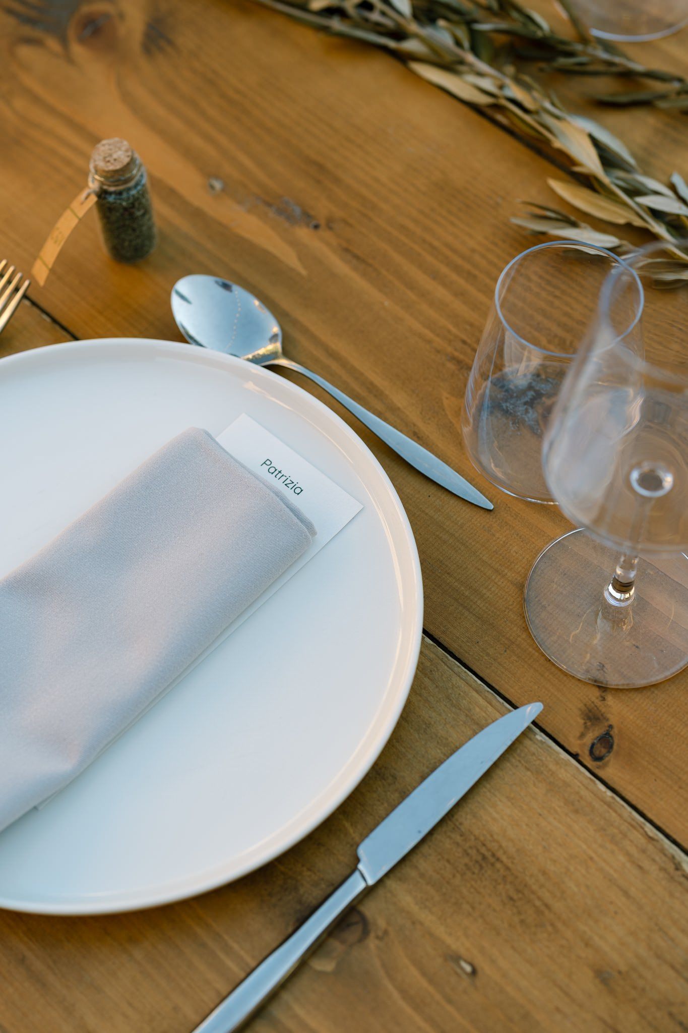 Close-up of elegant white dinner plates and glassware on wooden table.
