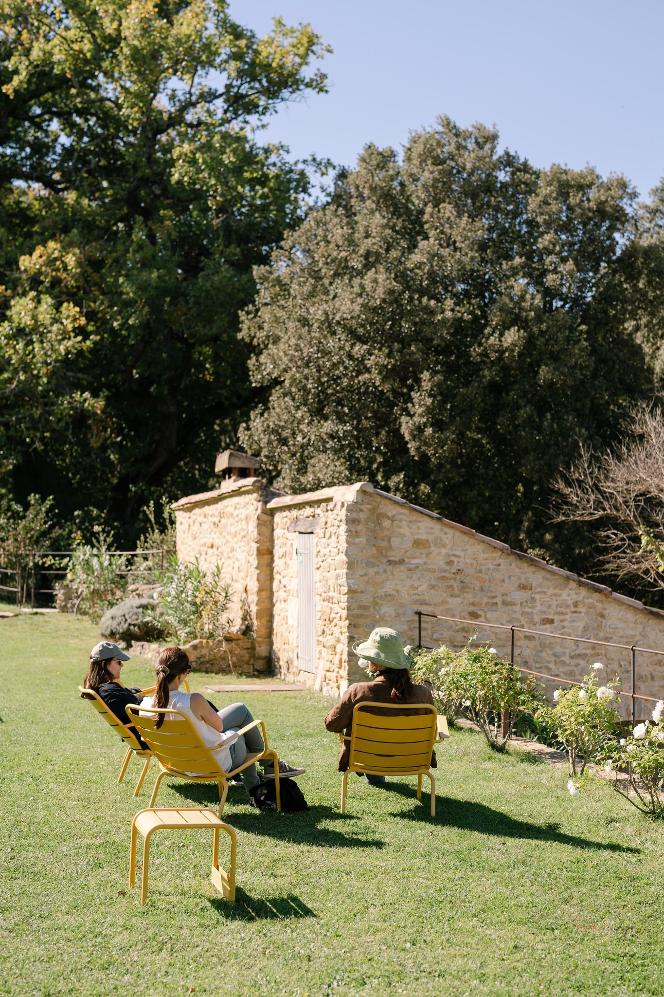 Yellow lounge chairs arranged on grass near stone building walls.