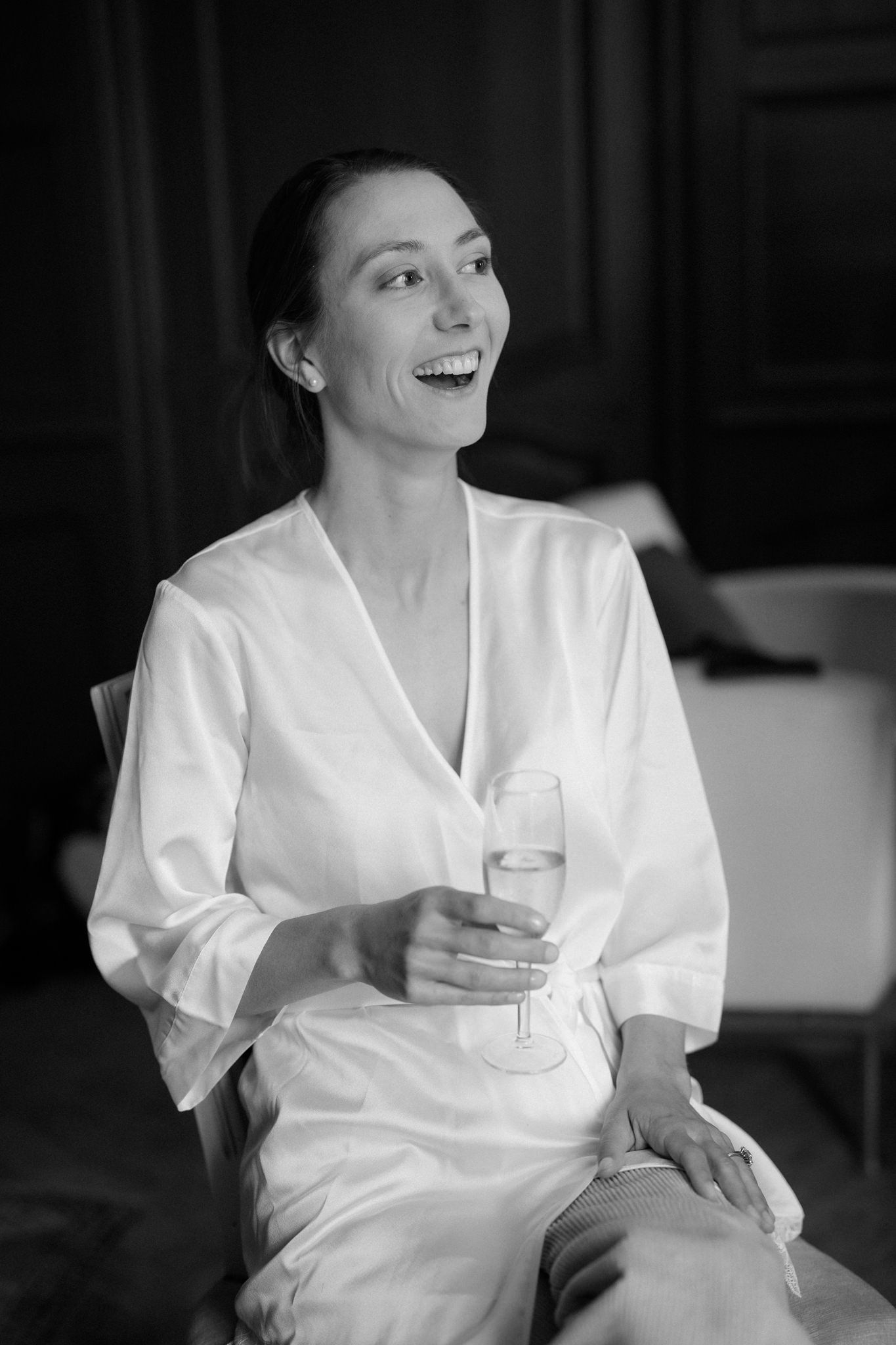 Person in white robe laughing while holding champagne.