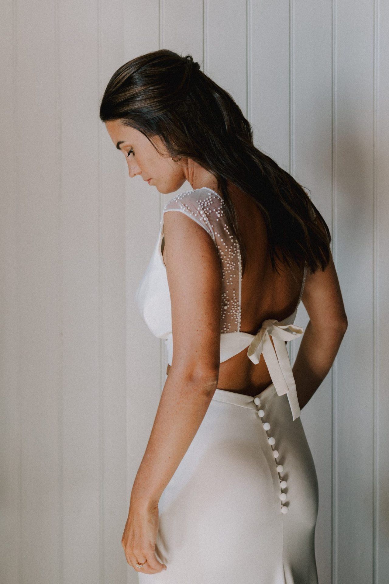 Back detail of a wedding dress with pearl buttons and lace accents.