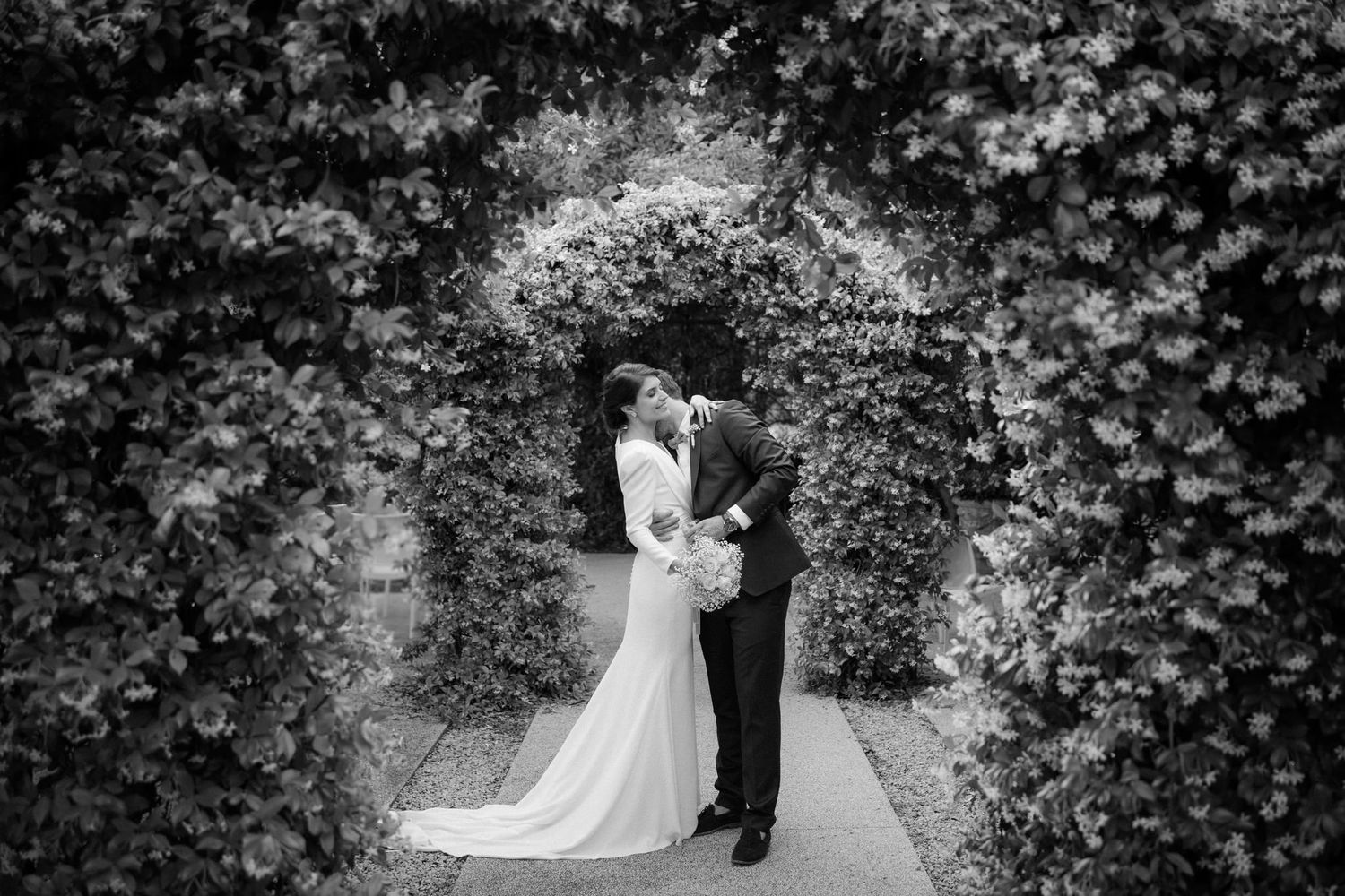 Wedding couple shares intimate moments among lush garden greenery.