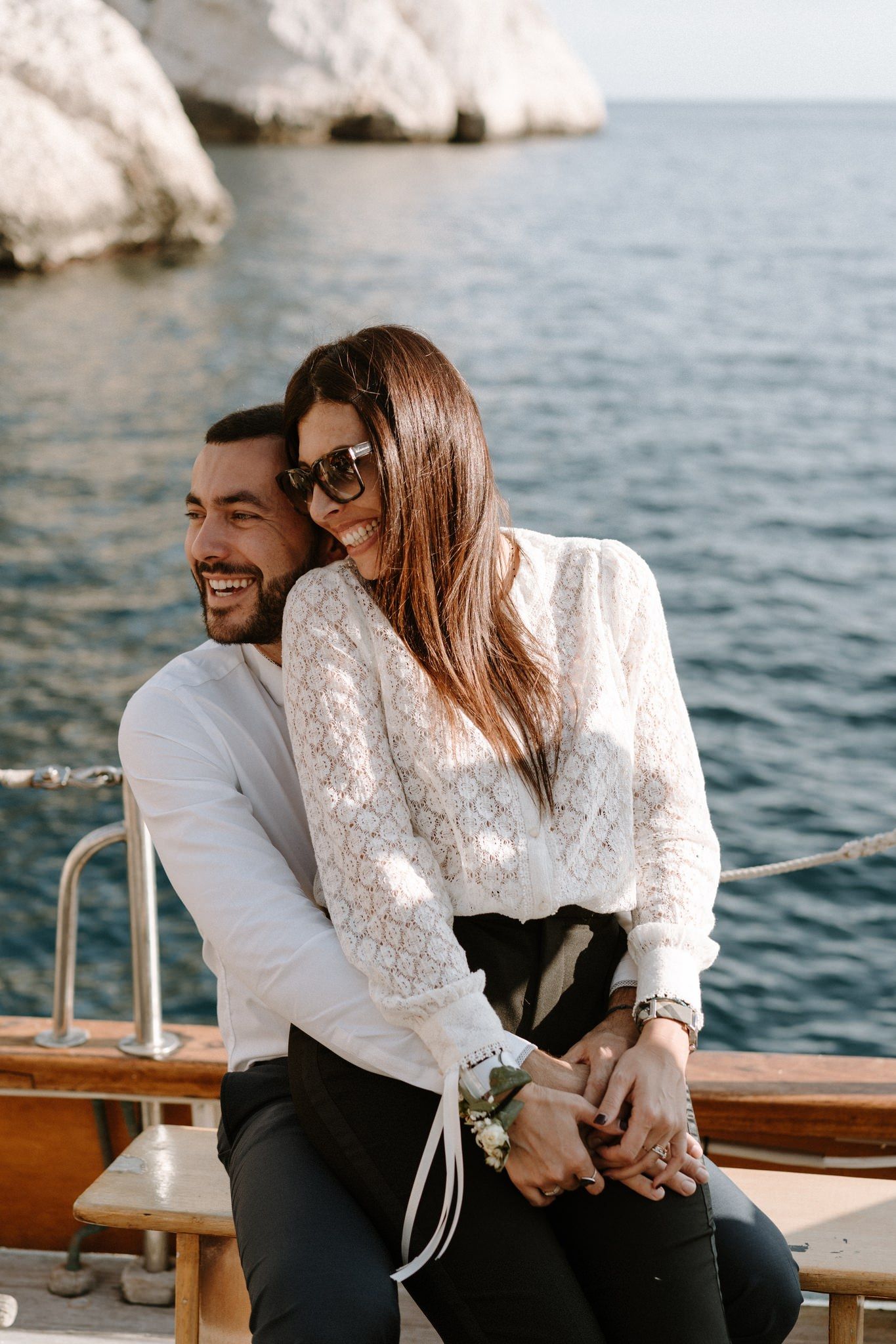 A couple enjoys a tender moment while sitting on a boat with ocean views.