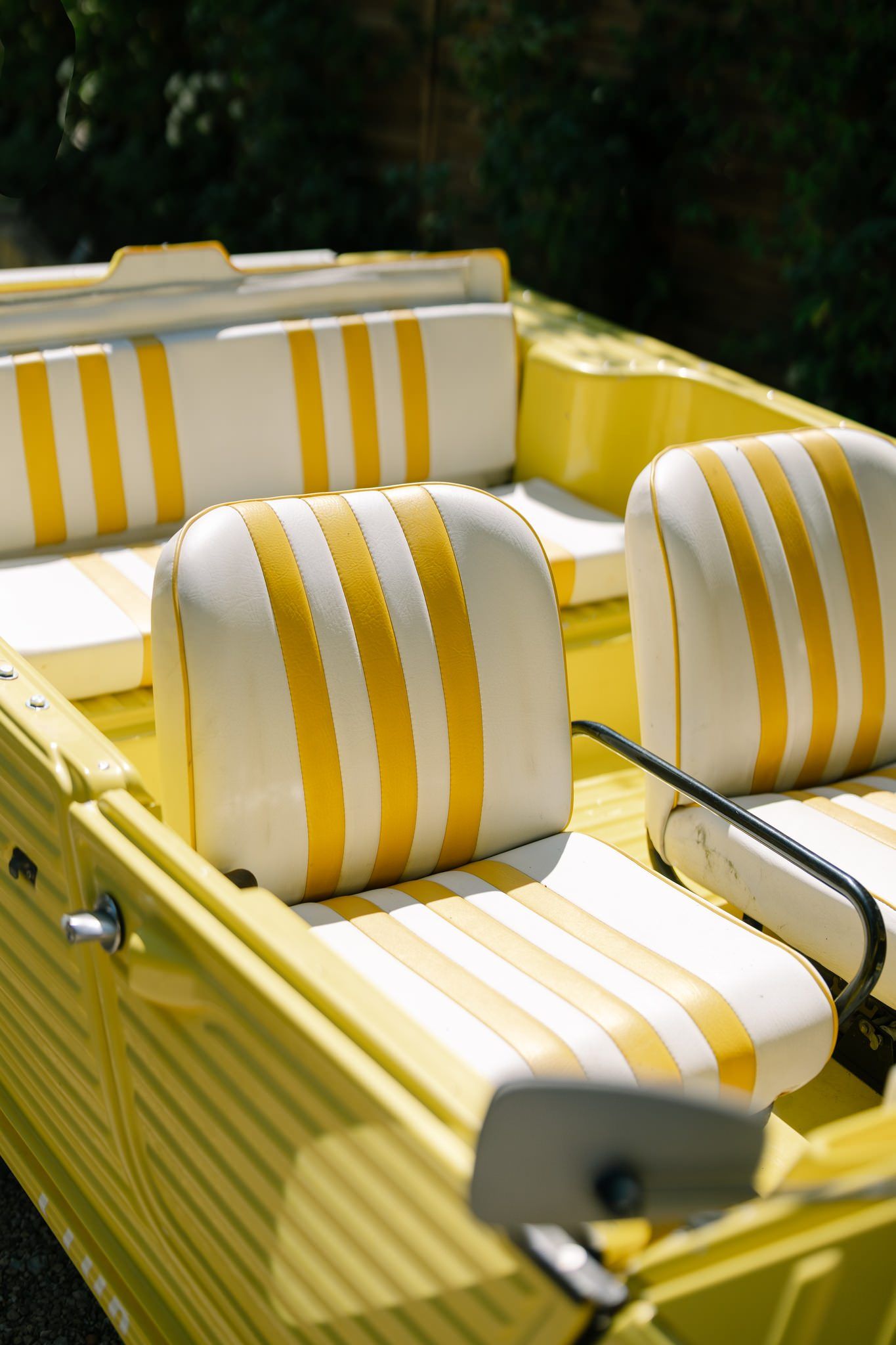 Yellow and white striped cushions on vintage boat seats in sunlight.