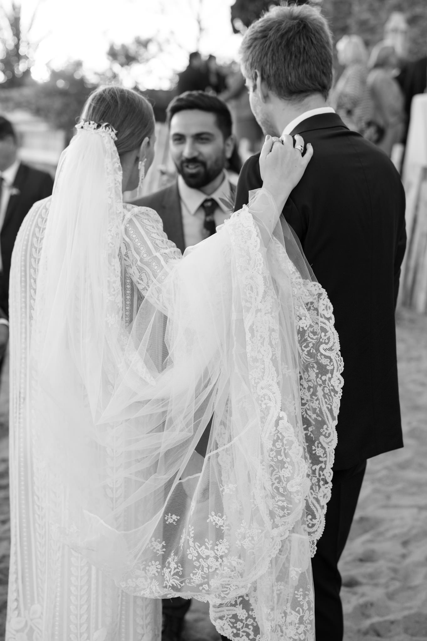 Elegant white lace wedding veil detail against formal black attire.