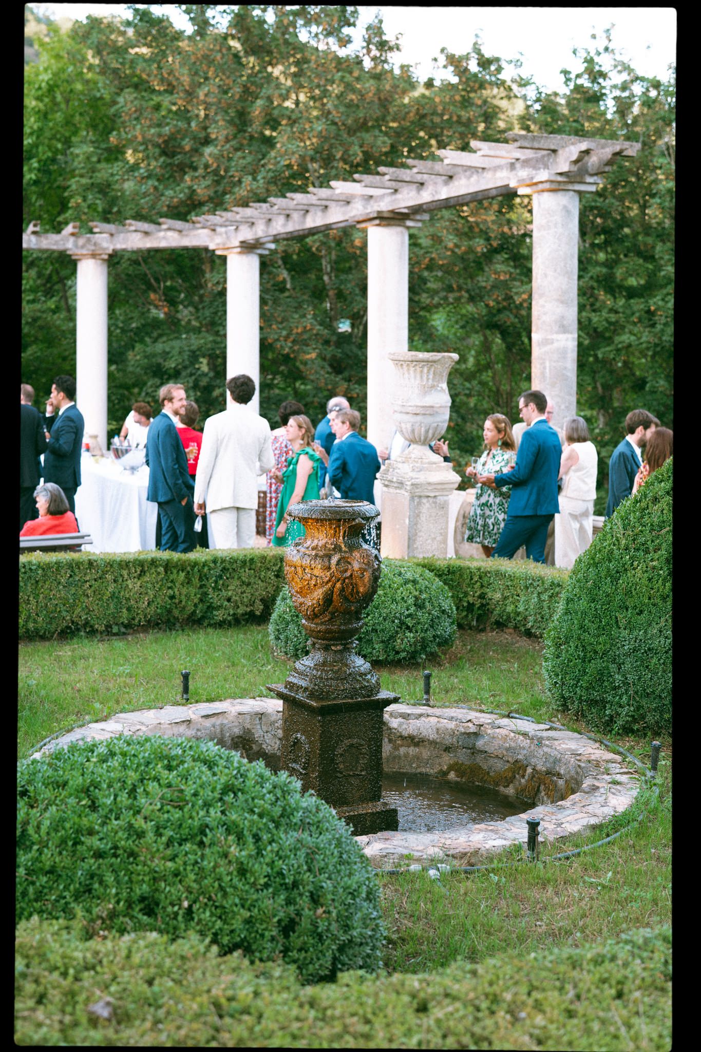 Elegant outdoor wedding reception setup with white pillars and manicured gardens.