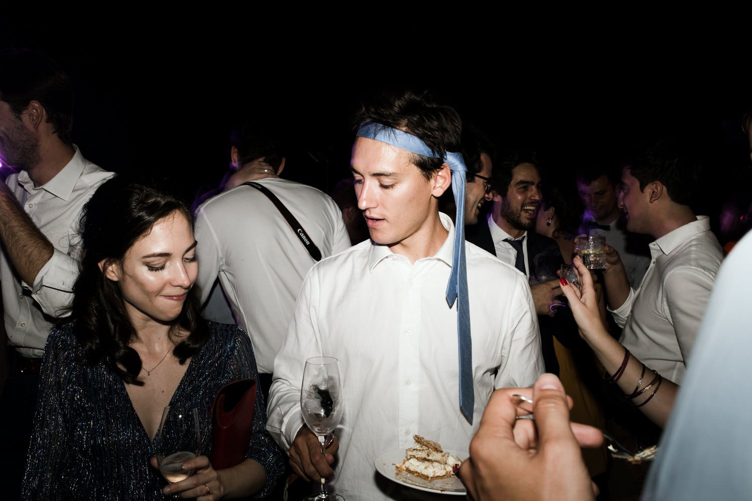 Lively dance party scene with guests moving in a dark venue with spotlights.