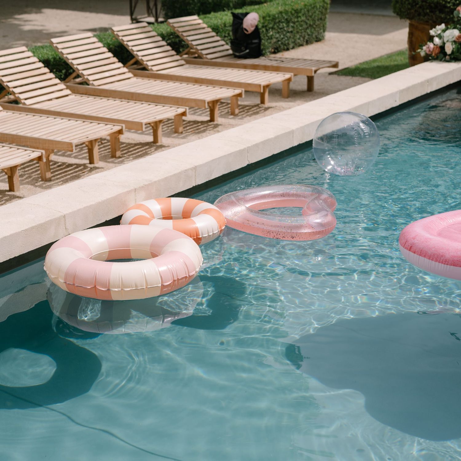 Pink pool floats drifting in a crystal clear swimming pool.