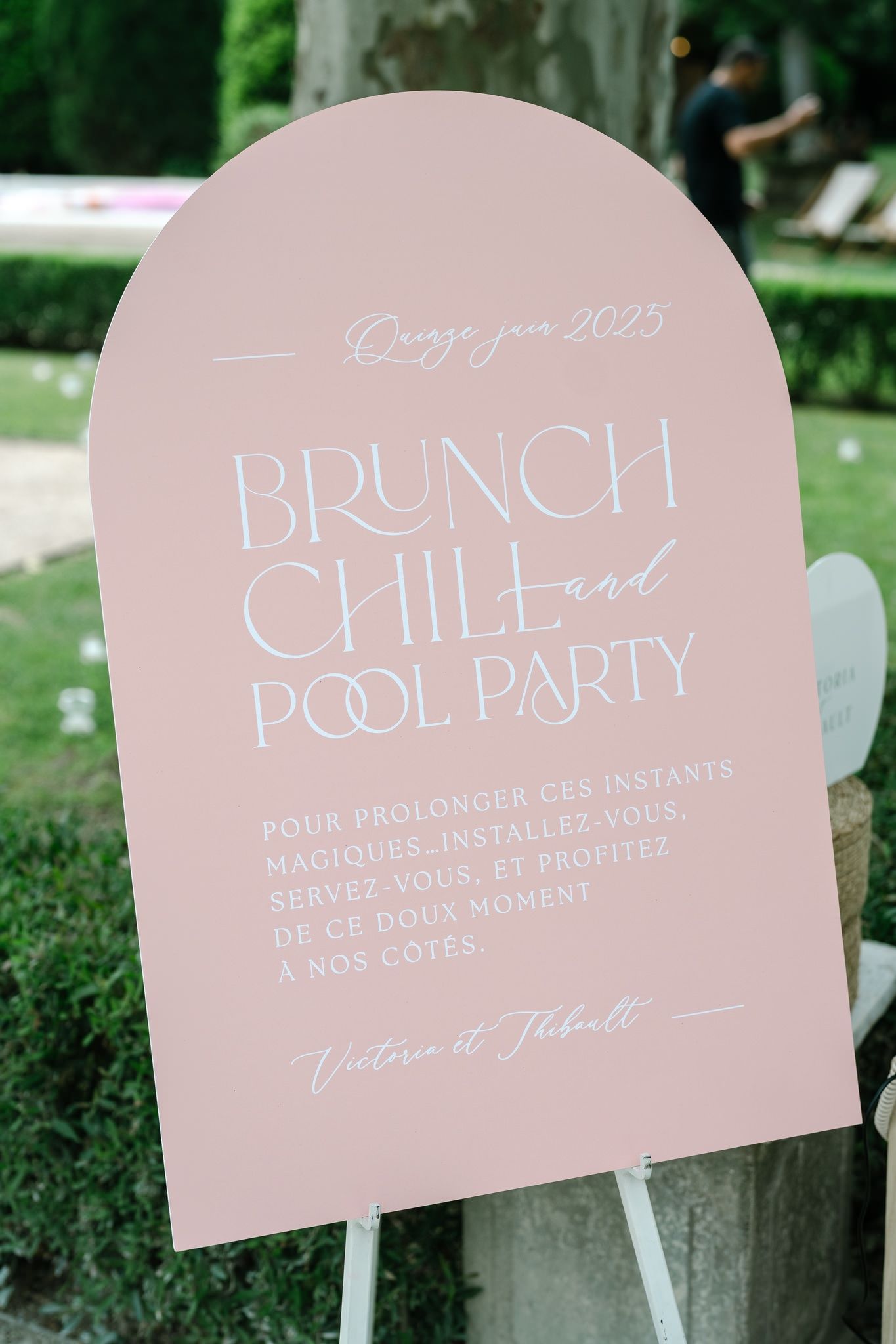 Pink wedding signage displaying 'Brunch Pool Party' text in elegant lettering.