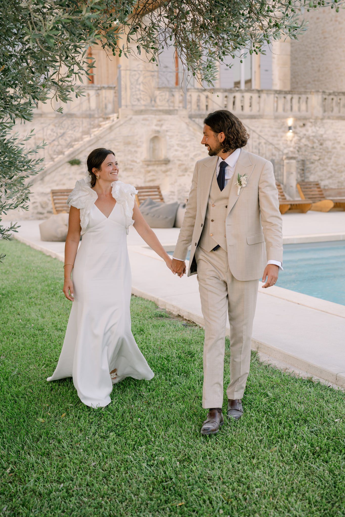 Elegant couple walking hand in hand by pool at luxury venue.