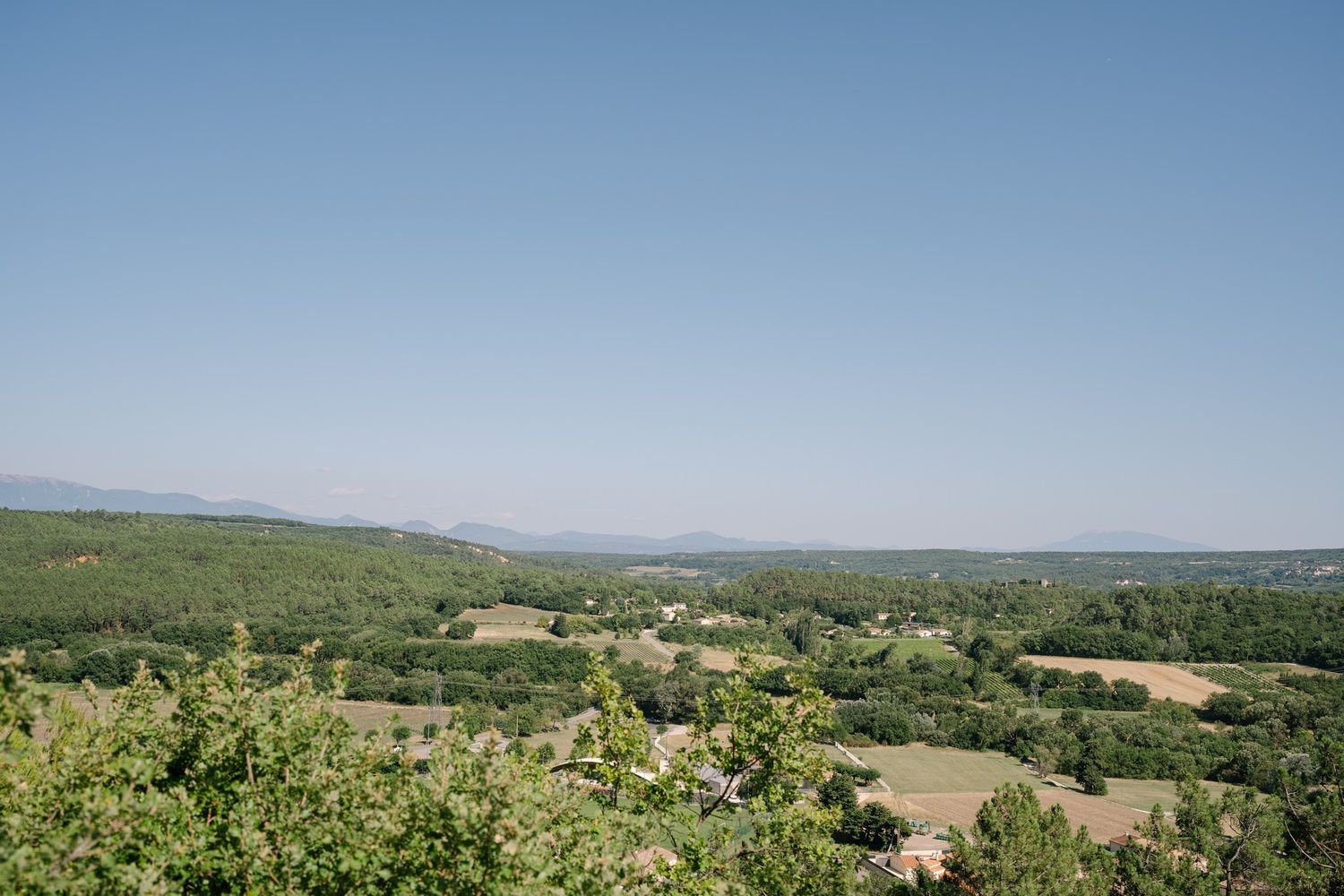 Scenic rolling hills and countryside landscape under clear blue summer sky.