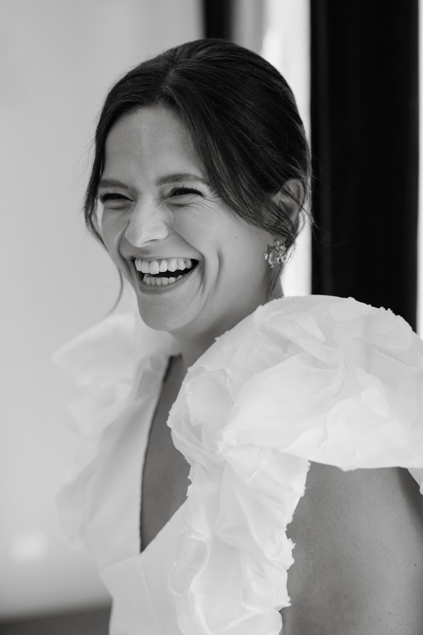 Black and white portrait series showing joyful laughter and genuine emotion in white ruffled dress.