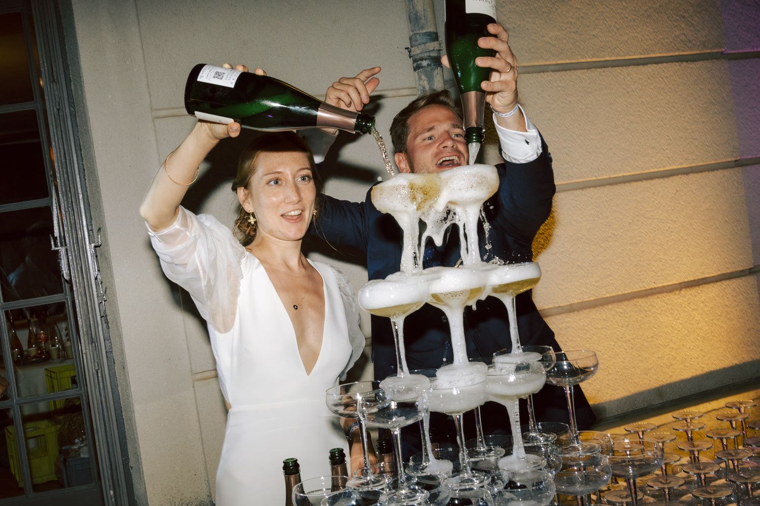 Celebratory moment pouring champagne into a tower of glasses at an event.