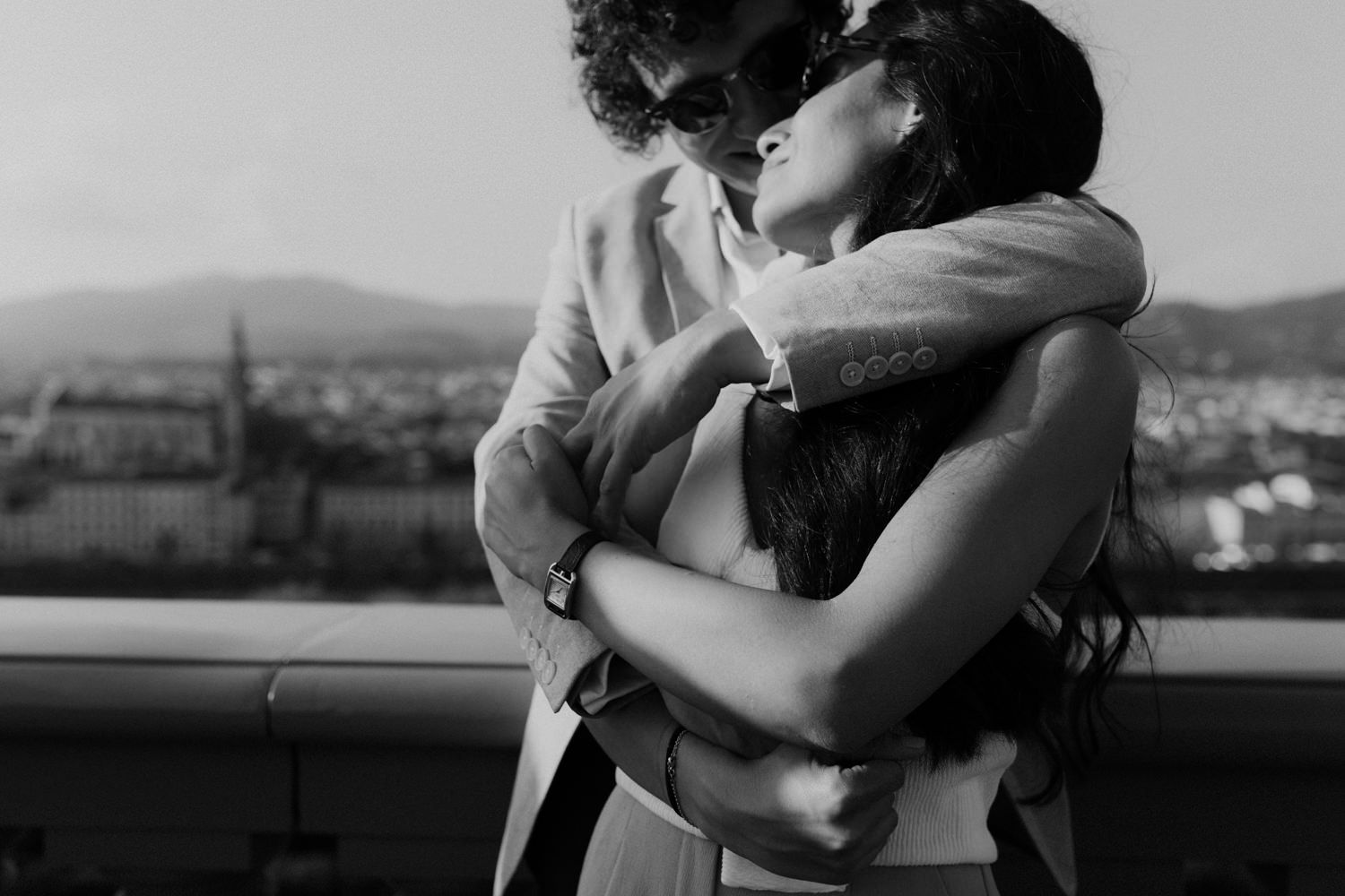 Intimate black and white moment against a cityscape backdrop.