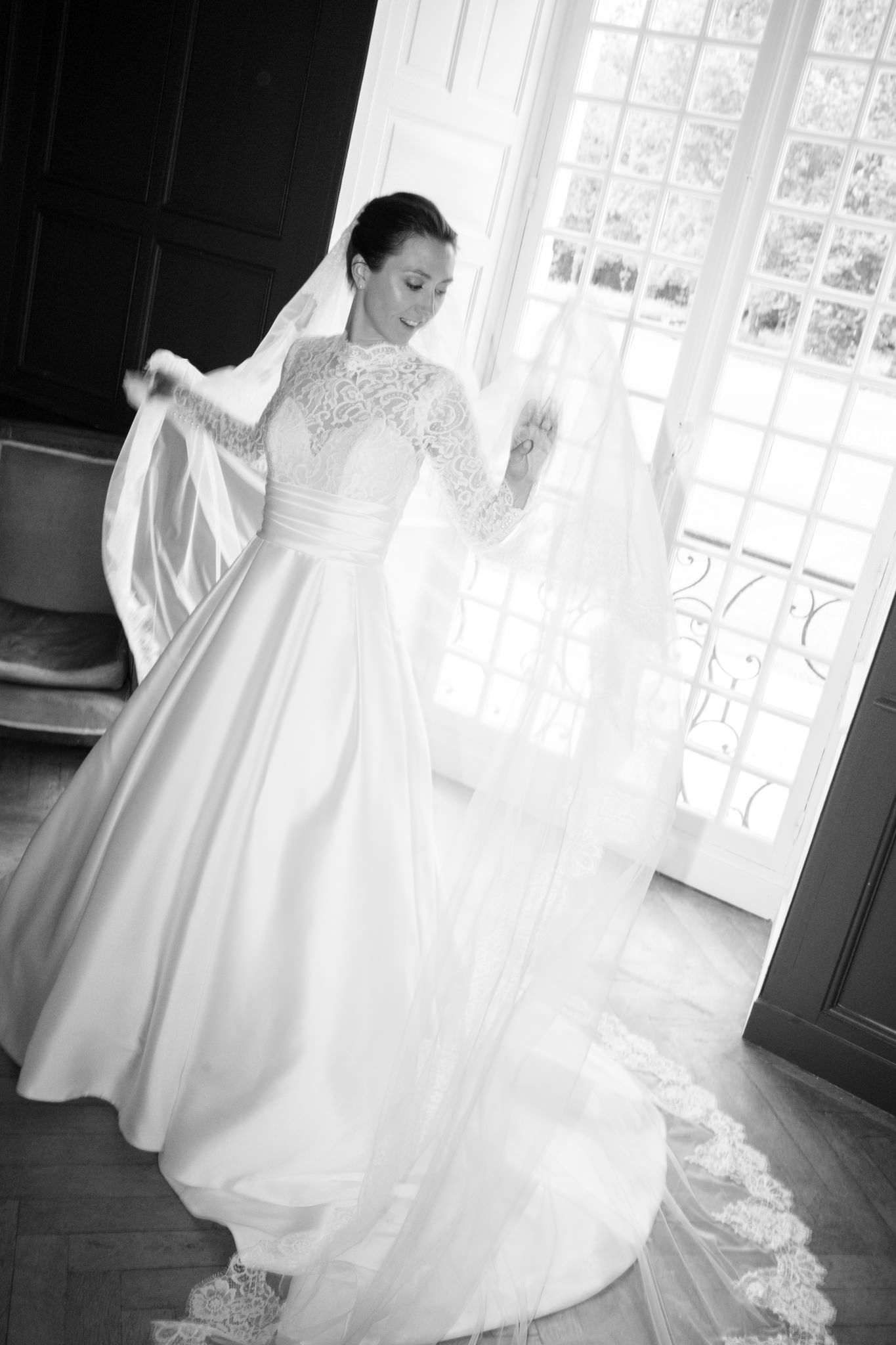 Ethereal black and white photos of a wedding dress near bright windows.