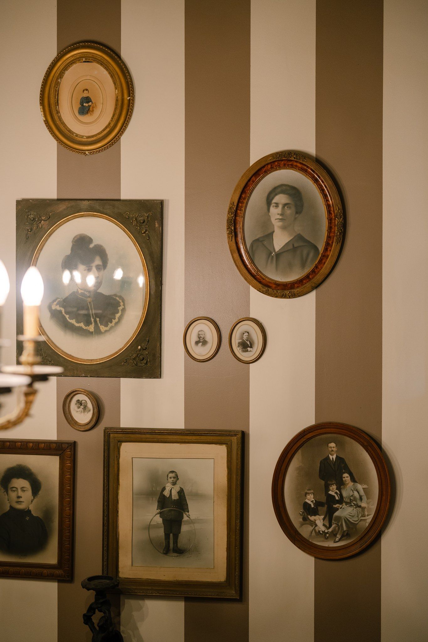 Vintage sepia photographs in ornate frames arranged on a striped wall.