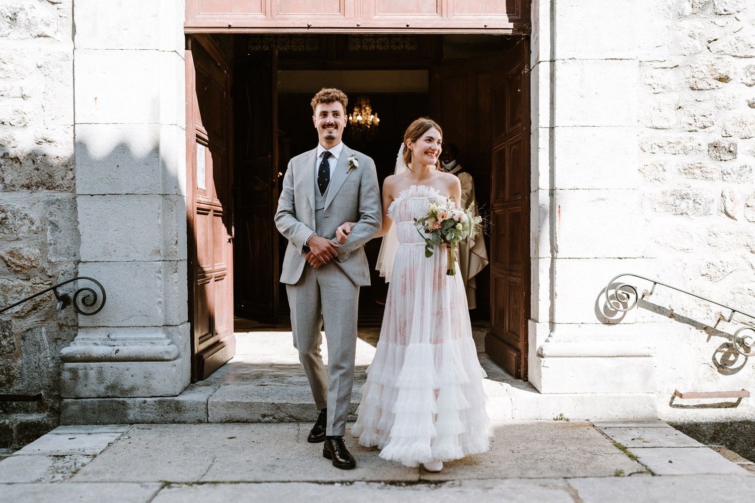 A couple exiting through stone church doorway after their wedding ceremony.