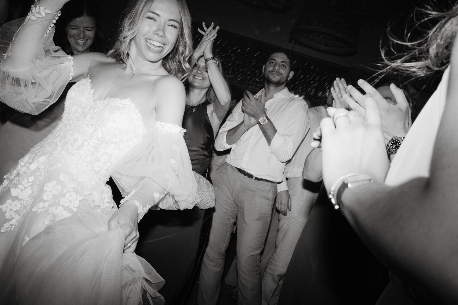 People dancing and celebrating in a dimly lit venue with enthusiastic energy.
